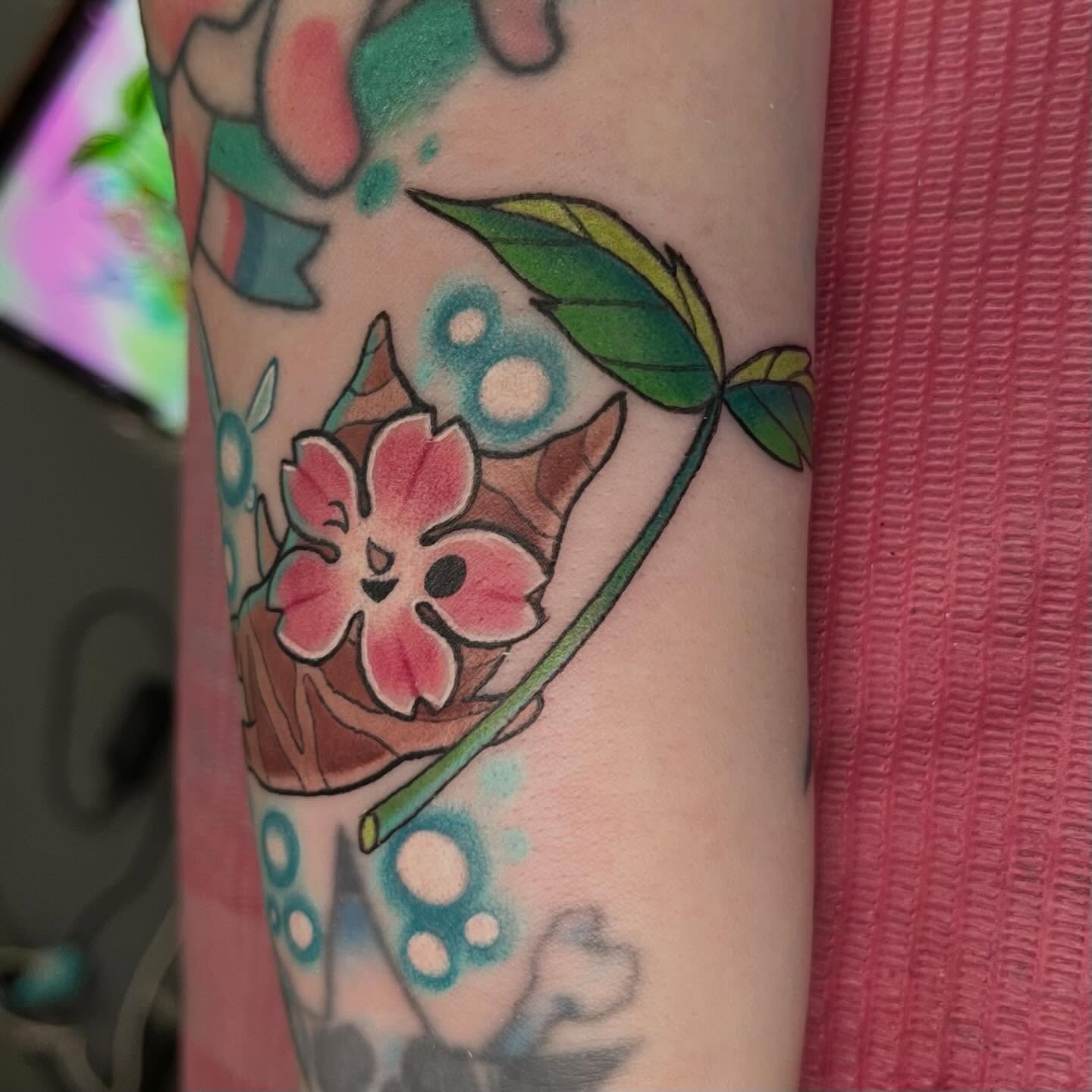 Flower and leaves watercolor tattoo on the forearm by Ash Wheeler