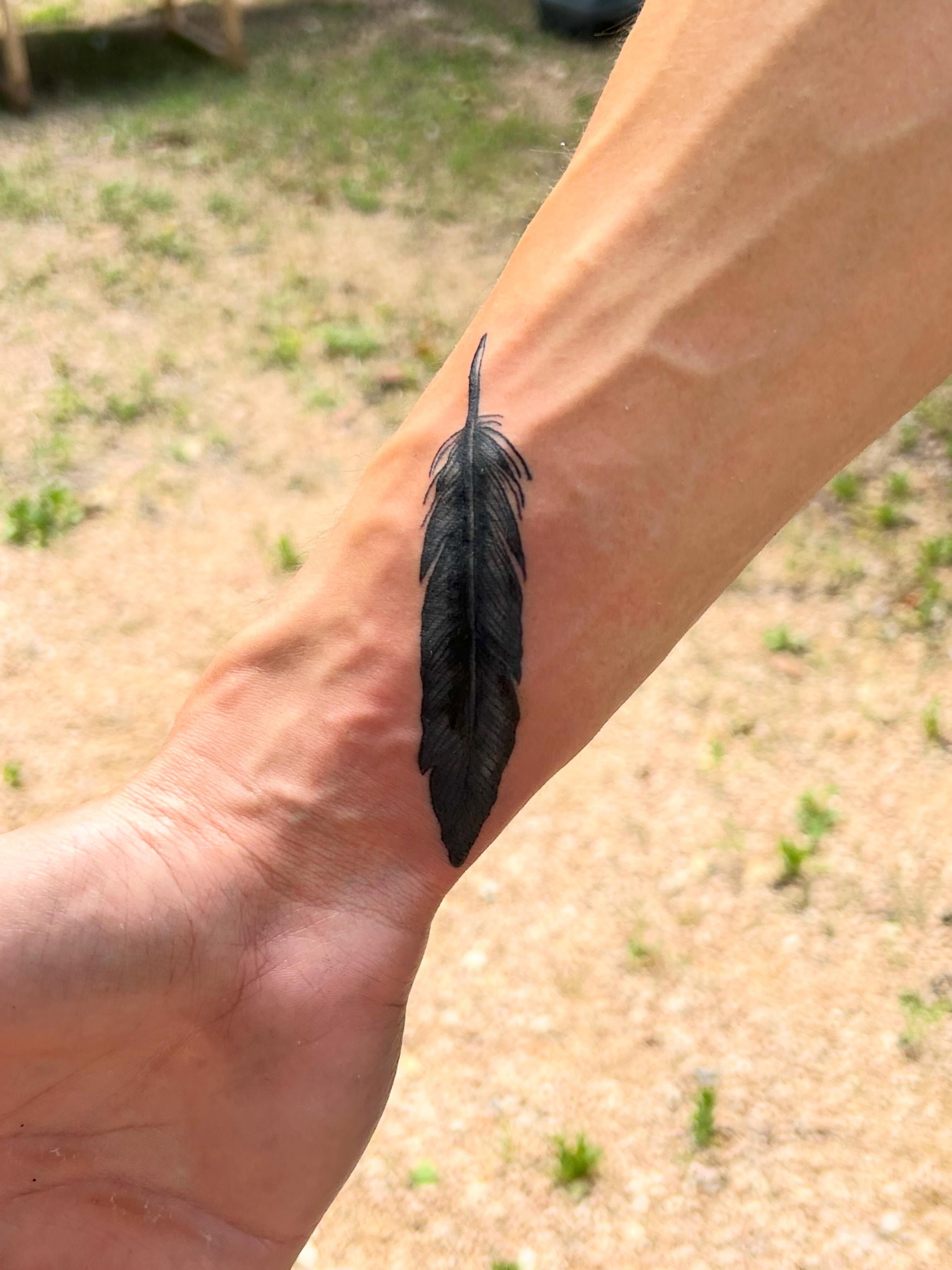 Feather black and grey tattoo on the forearm by Miss Katie