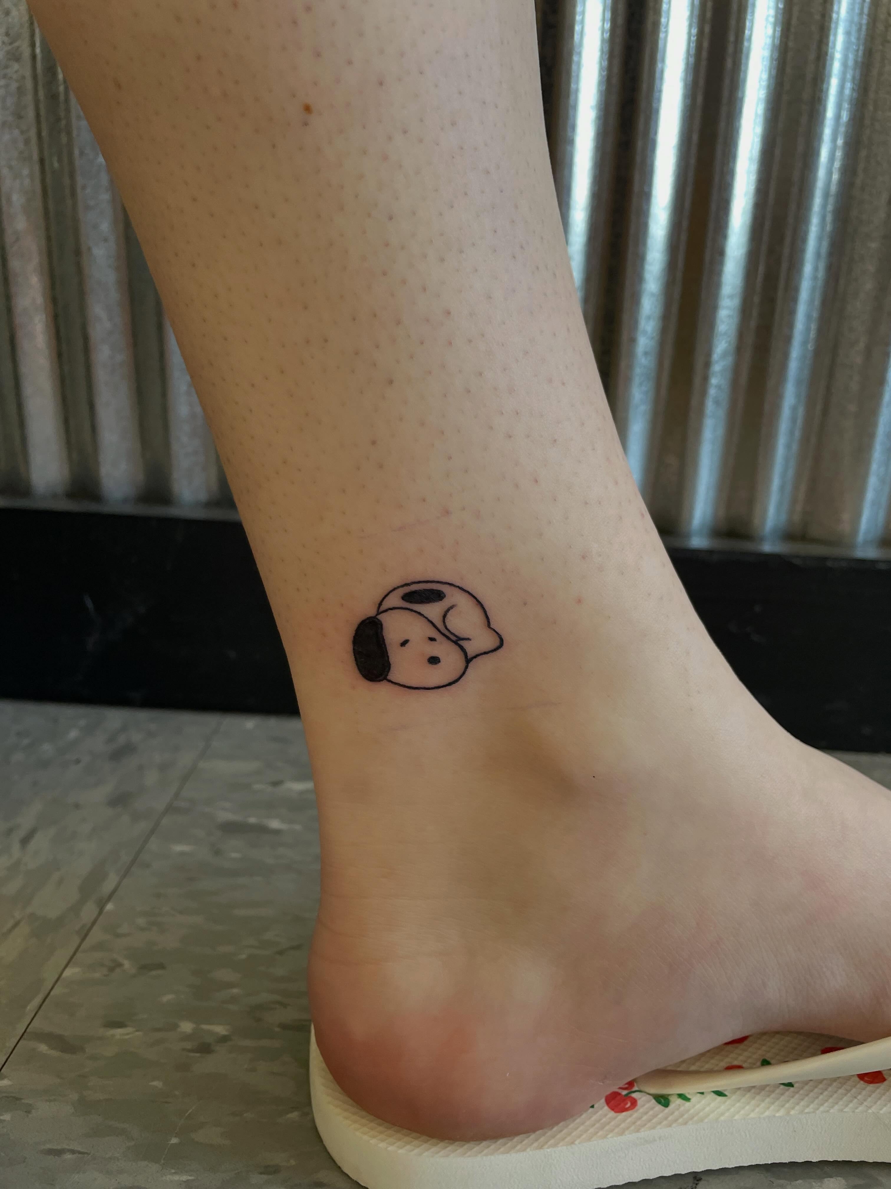 Sleeping dog minimalist tattoo on the foot by Mallory Moore