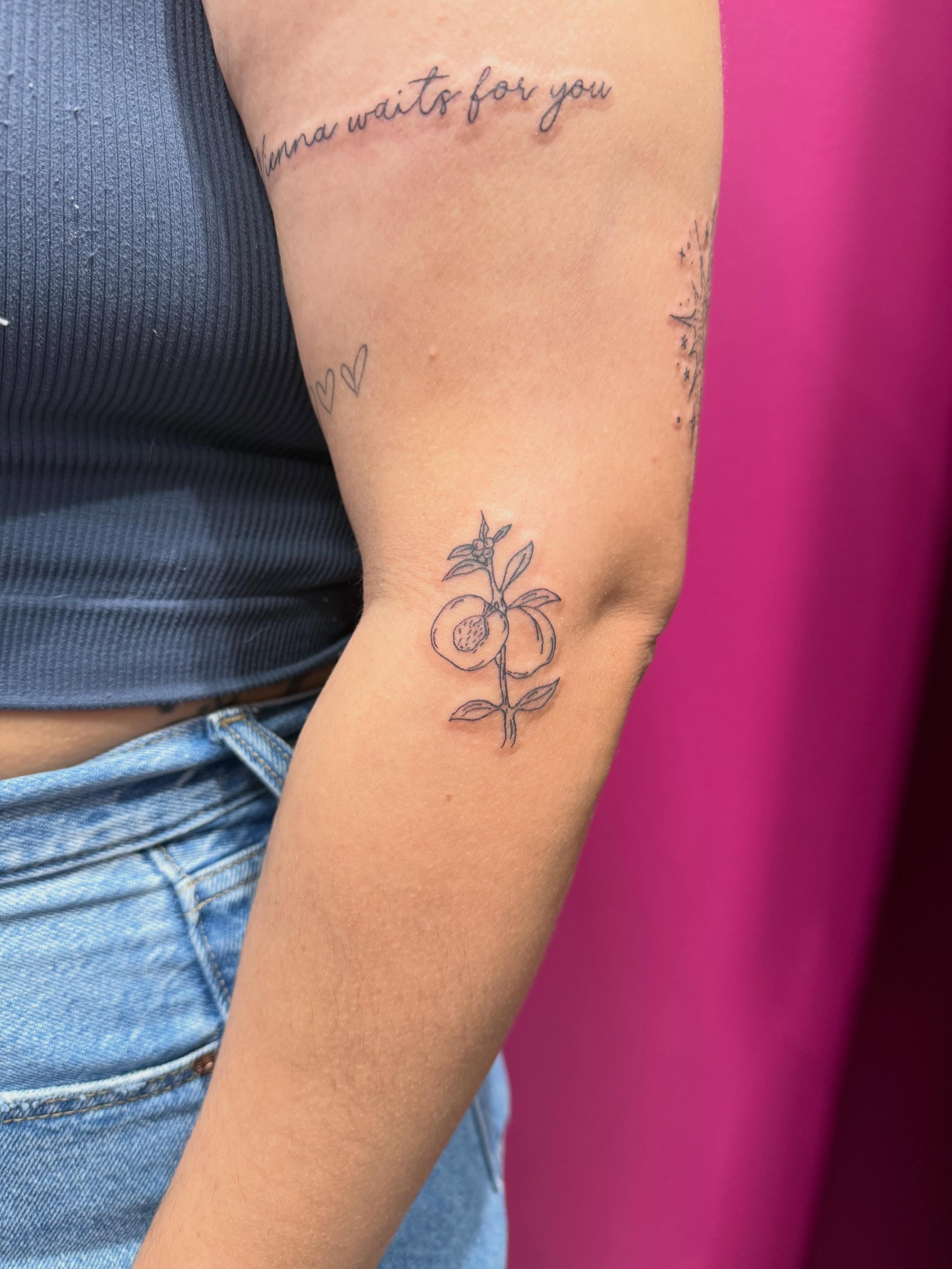 Peach and leaf fine line tattoo on the forearm by fine line tattoos