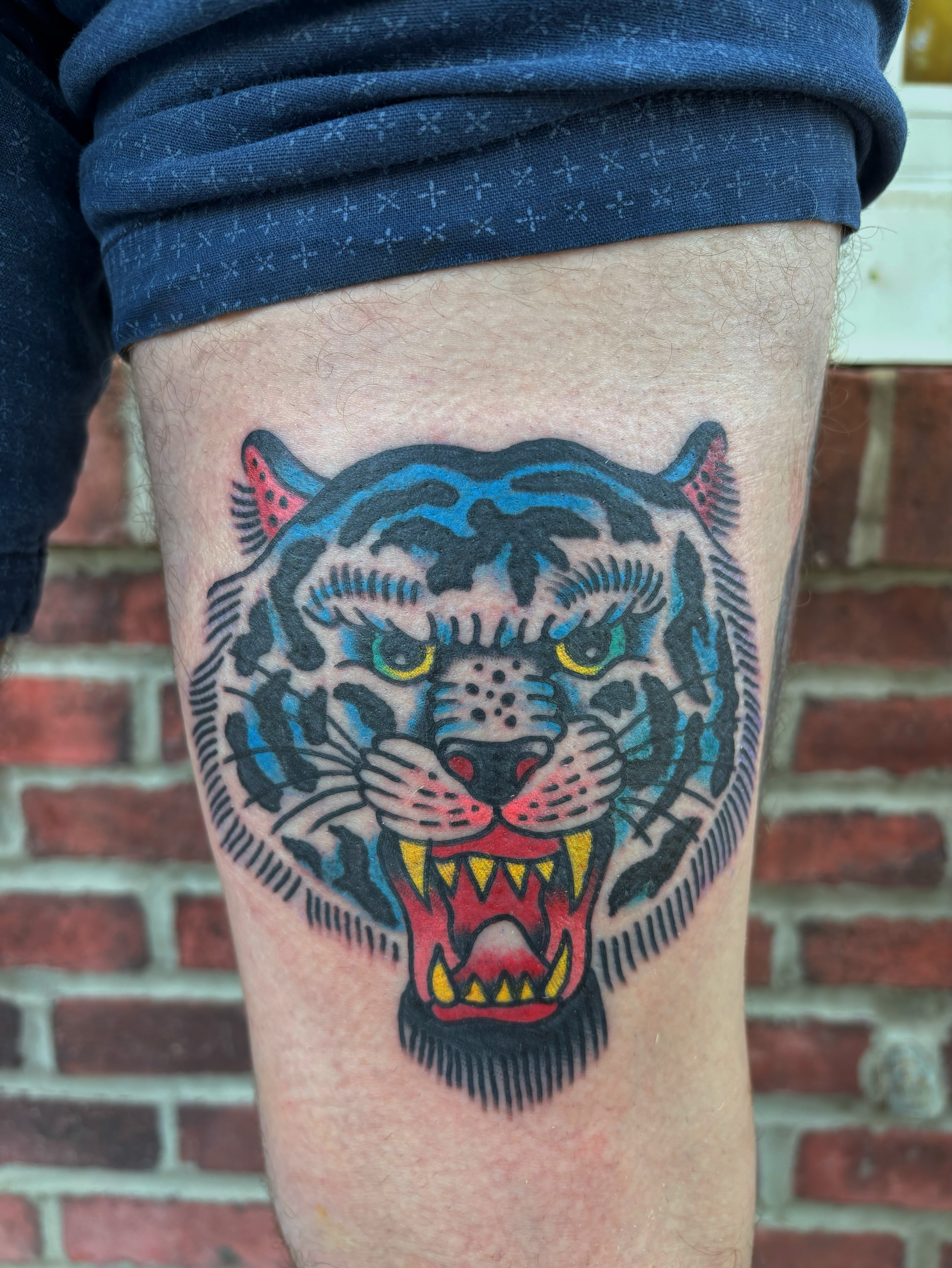 Tiger head American traditional tattoo on the thigh by Cooper Reichwein