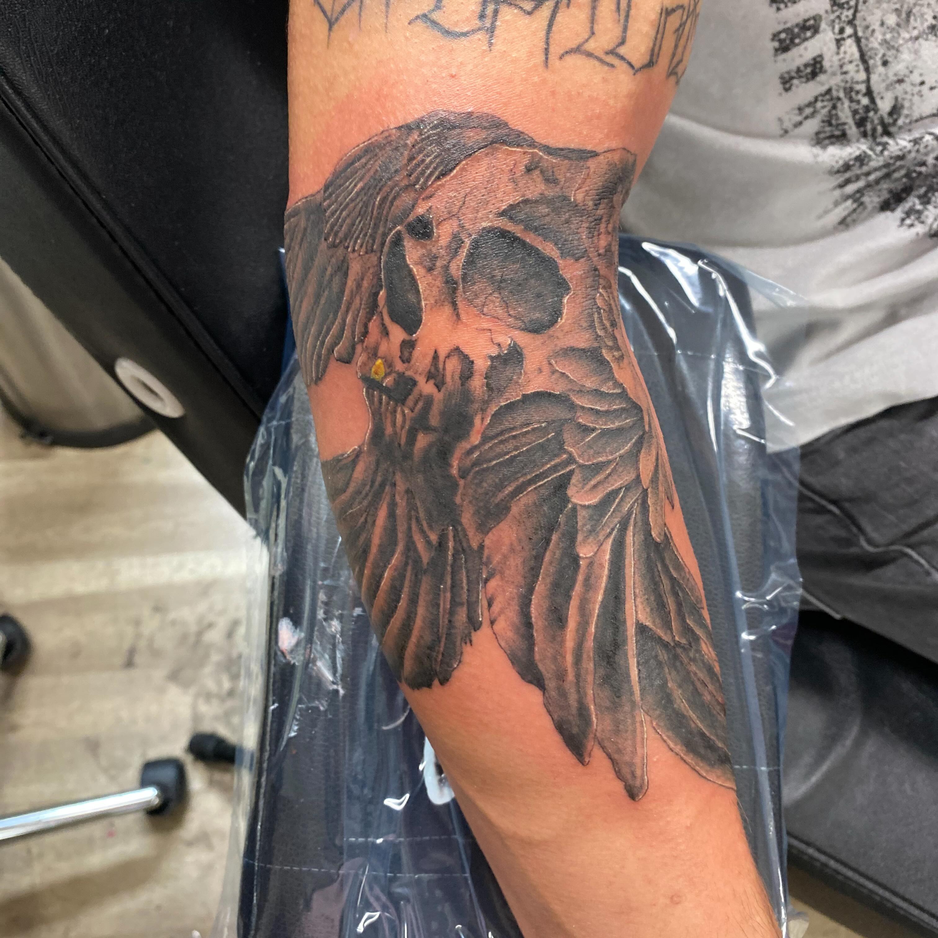 Skull with wings realism tattoo on the forearm by D. Davis