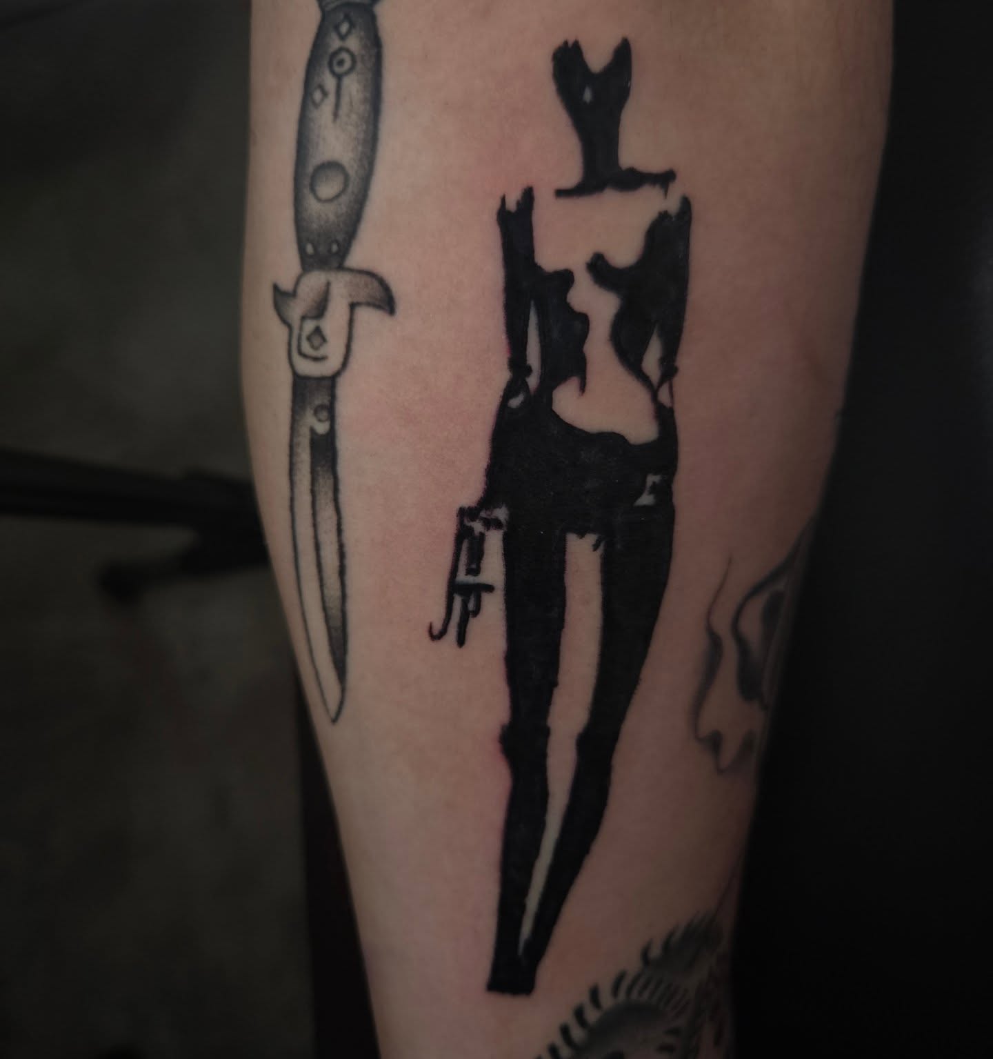 Knife and silhouette black and grey tattoo on the forearm by Lane
