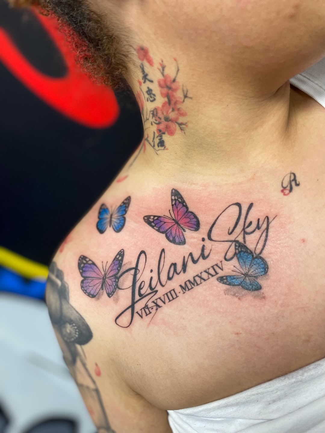 Name and roman numerals with butterflies fine line tattoo on the chest by Antonio