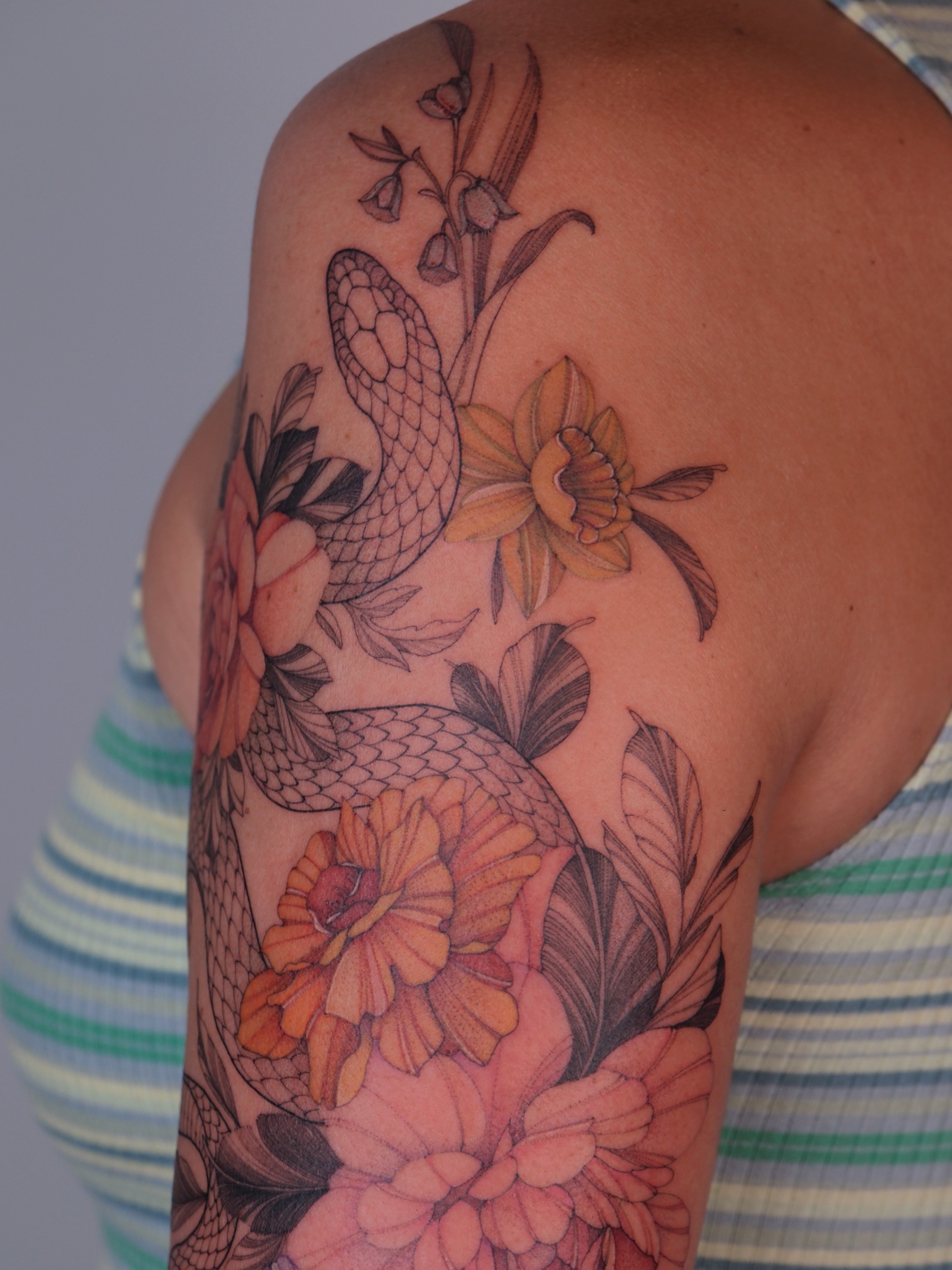 Snake and flowers realism tattoo on the shoulder by Flower Tattoo Sf