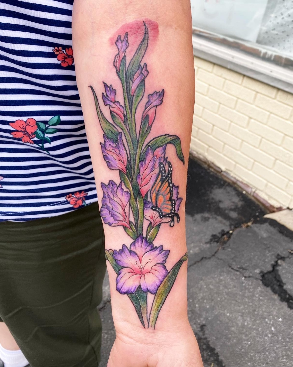 Gladiolus and butterfly watercolor tattoo on the forearm by Dani Di Pietrantonio
