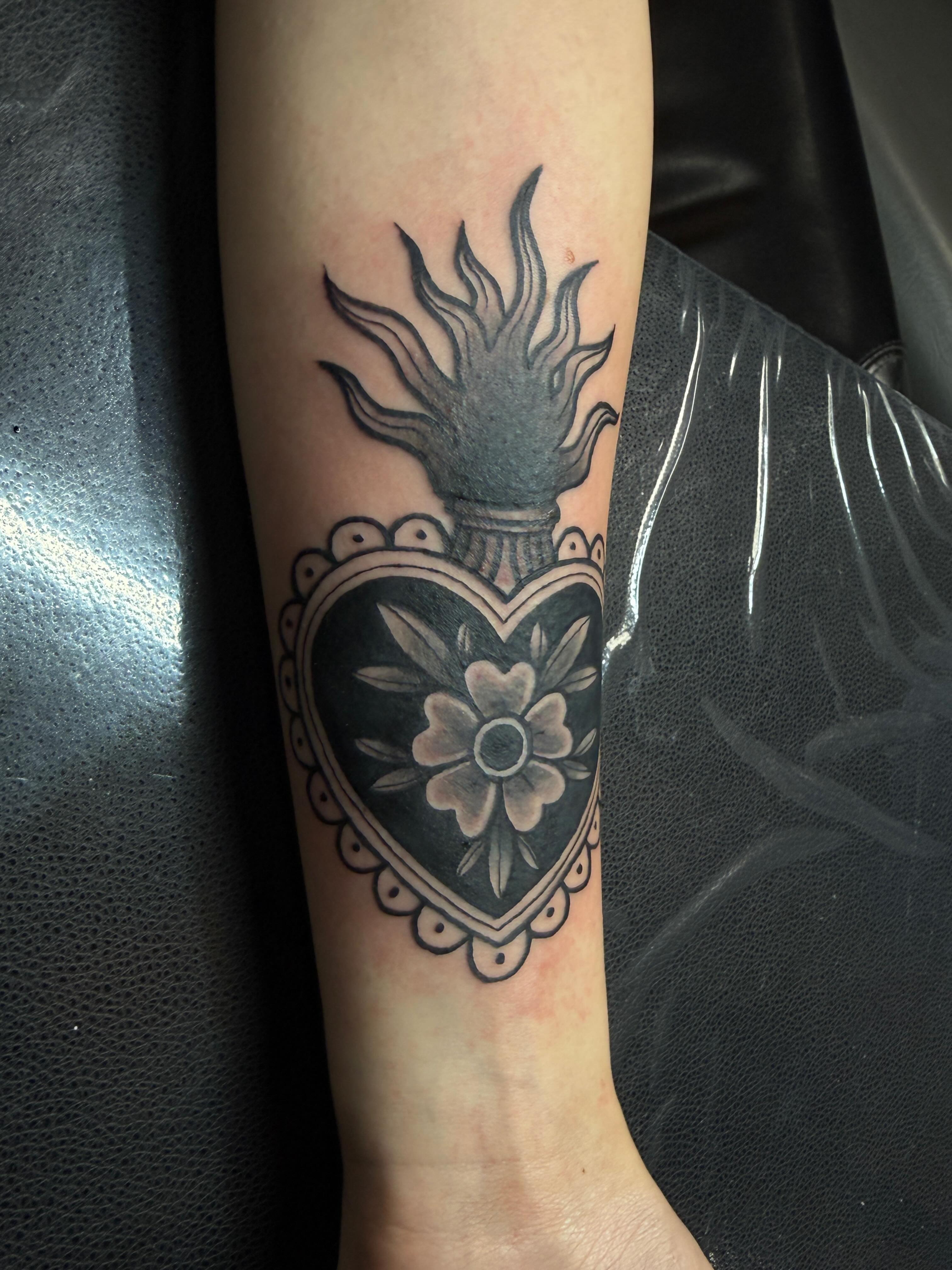 Heart with floral and flame black and grey tattoo on the forearm by sᴋᴇᴛᴄʜᴇᴅ