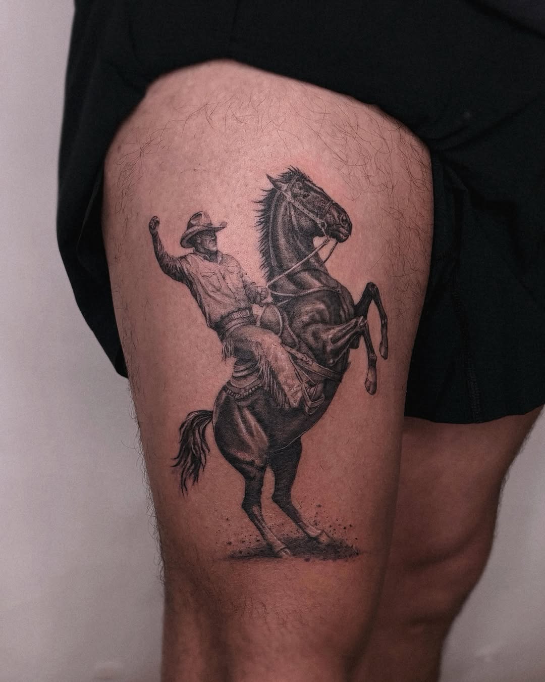 Cowboy riding a bucking horse realism tattoo on the thigh by Gabriel