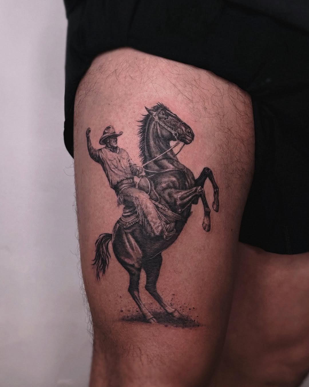 Cowboy riding a rearing horse realism tattoo on the thigh by Gabriel