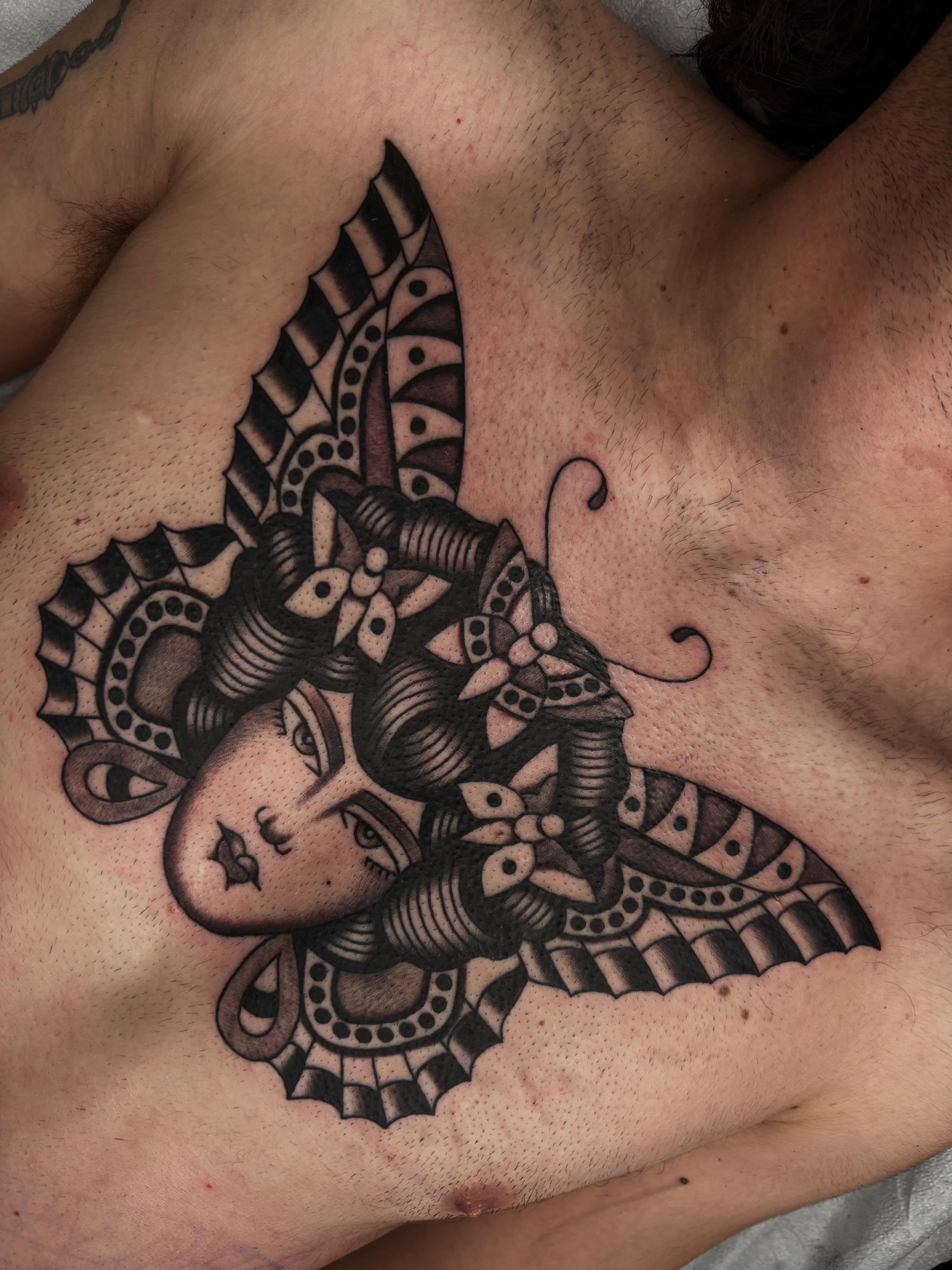 Woman's face ornamental tattoo on the chest by Claire Anderson