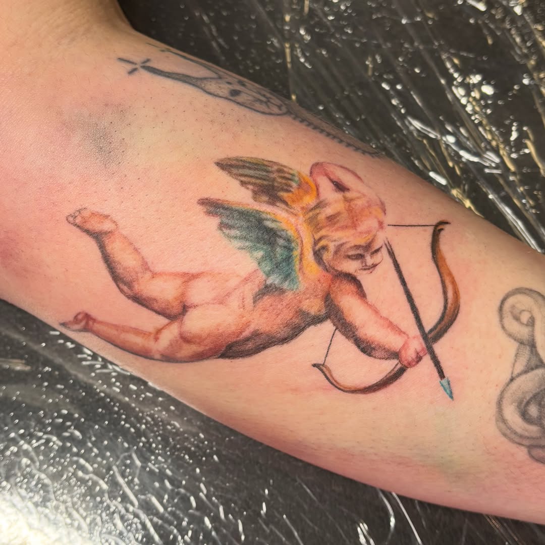 Cherub with bow realism tattoo on the forearm by jordy