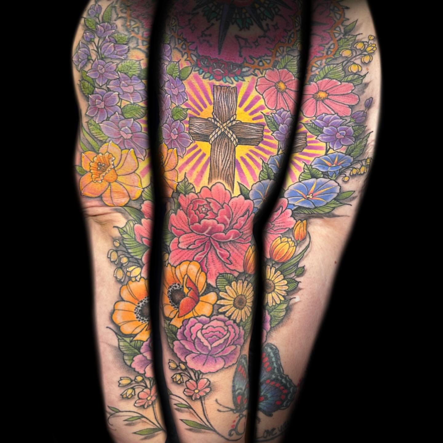 Cross surrounded by flowers American traditional tattoo on the forearm by Kelsea Weir McCree