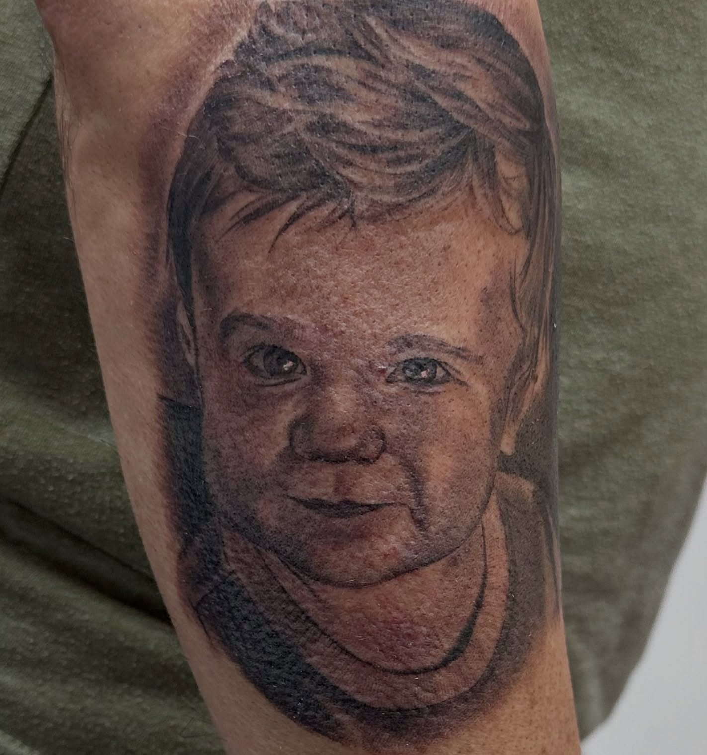 Child portrait realism tattoo on the forearm by Matthew Doherty
