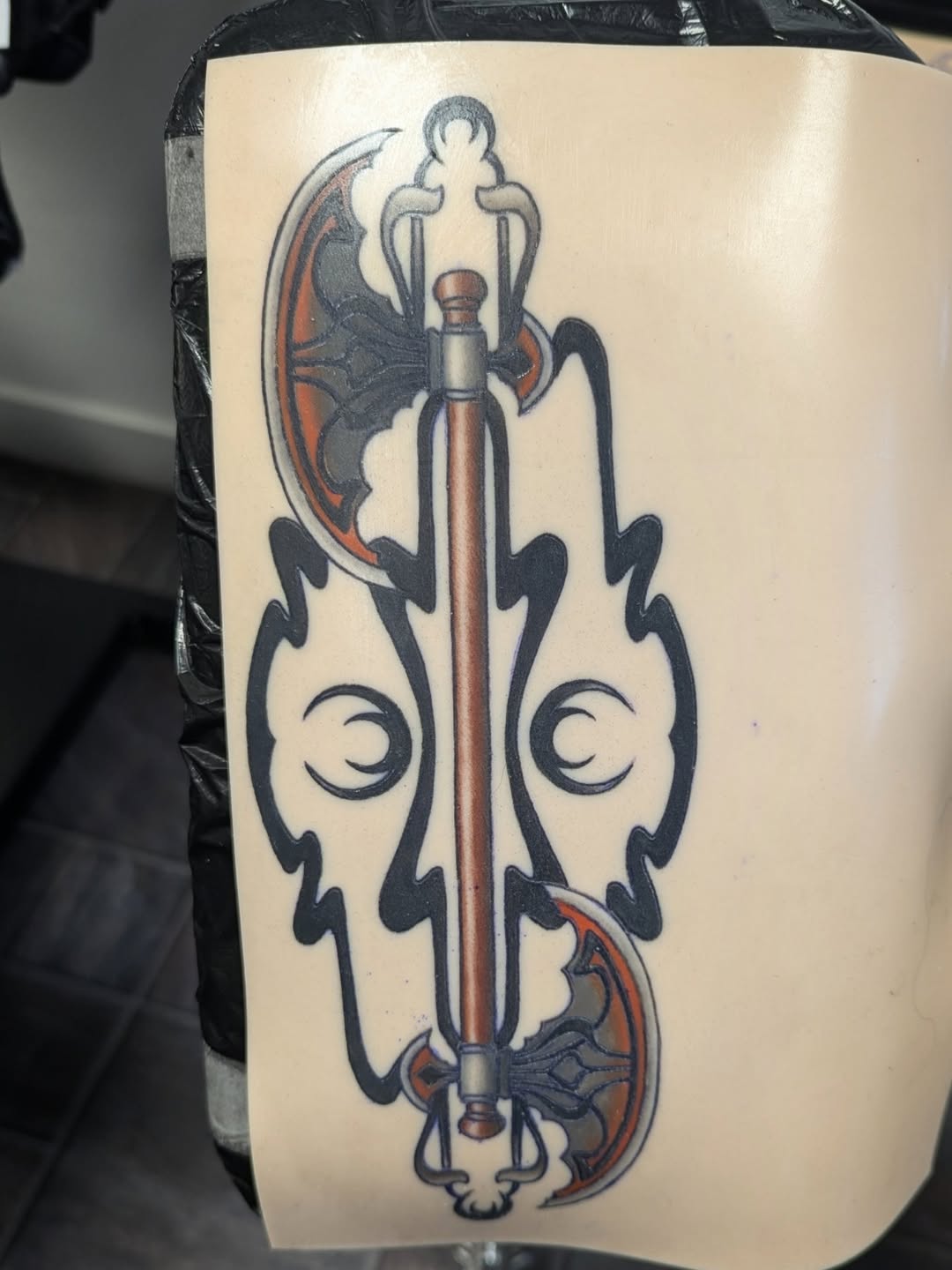 Double-headed axe with tribal elements tattoo on the forearm by Payton