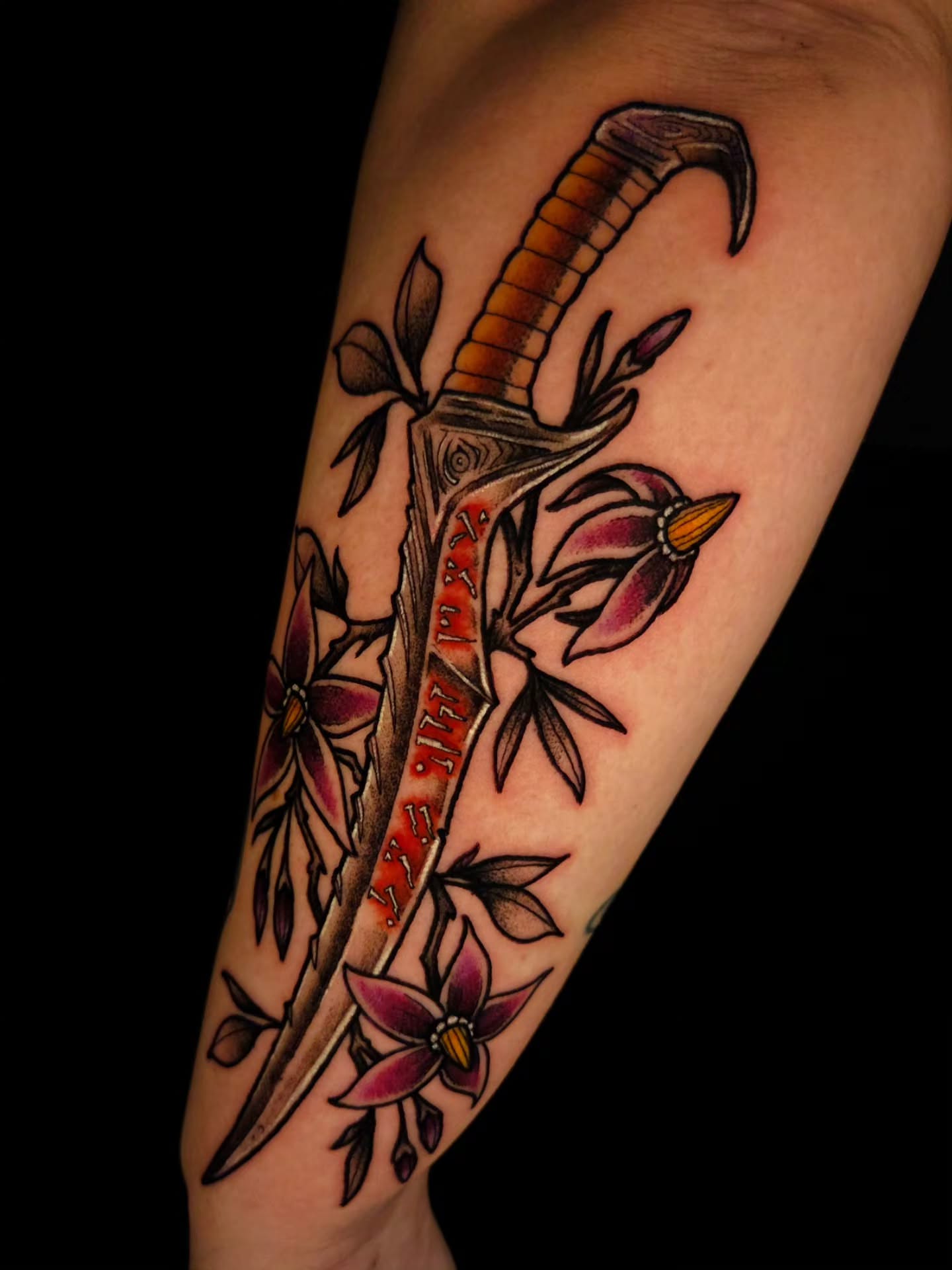 Sword and flowers American traditional tattoo on the forearm by Ian Kiser