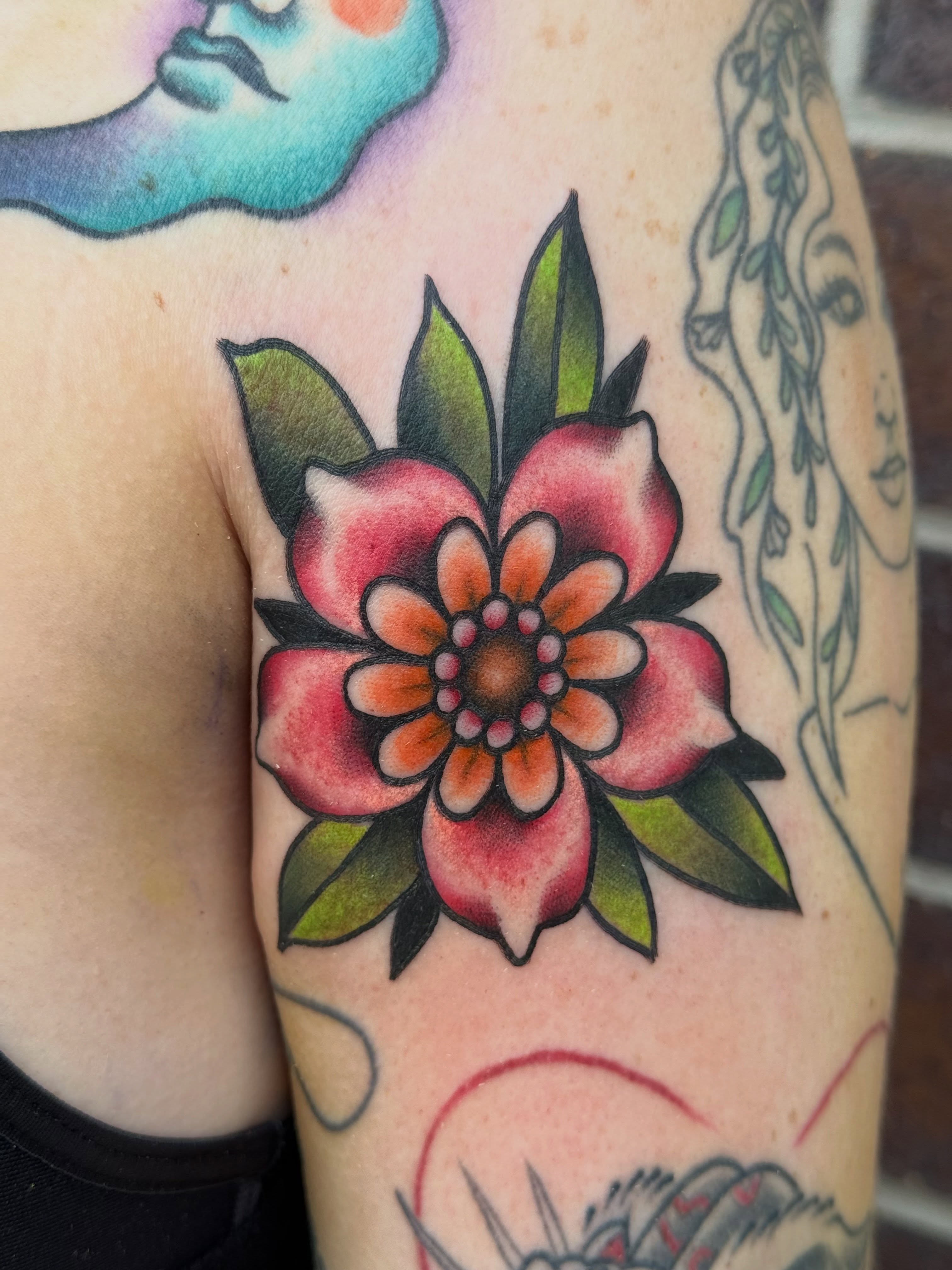 Flower American traditional tattoo on the upper arm by Kelsey Louis, Iowa City, Iowa