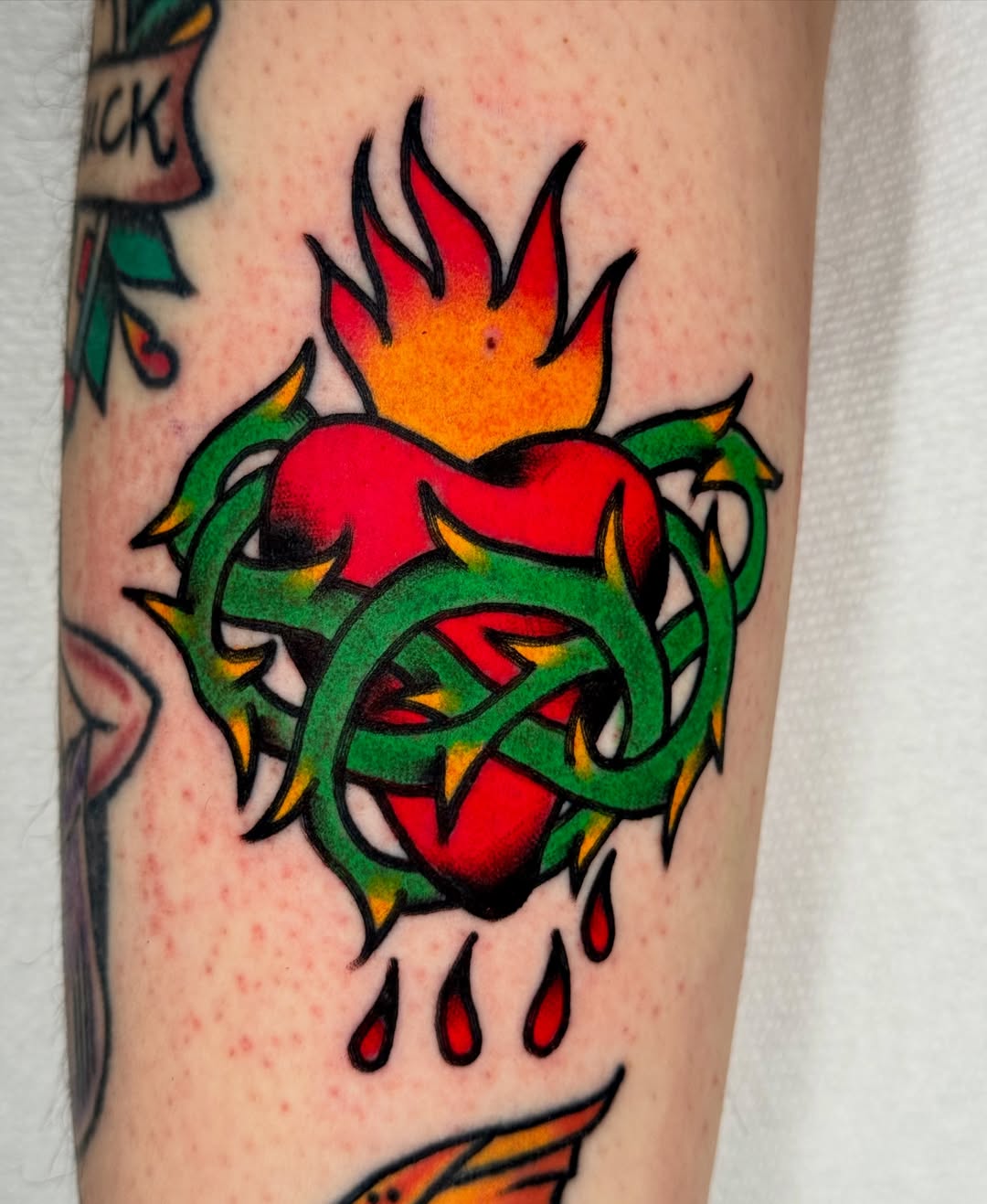 Flaming heart American traditional tattoo on the forearm by Joe Bear Tattooer