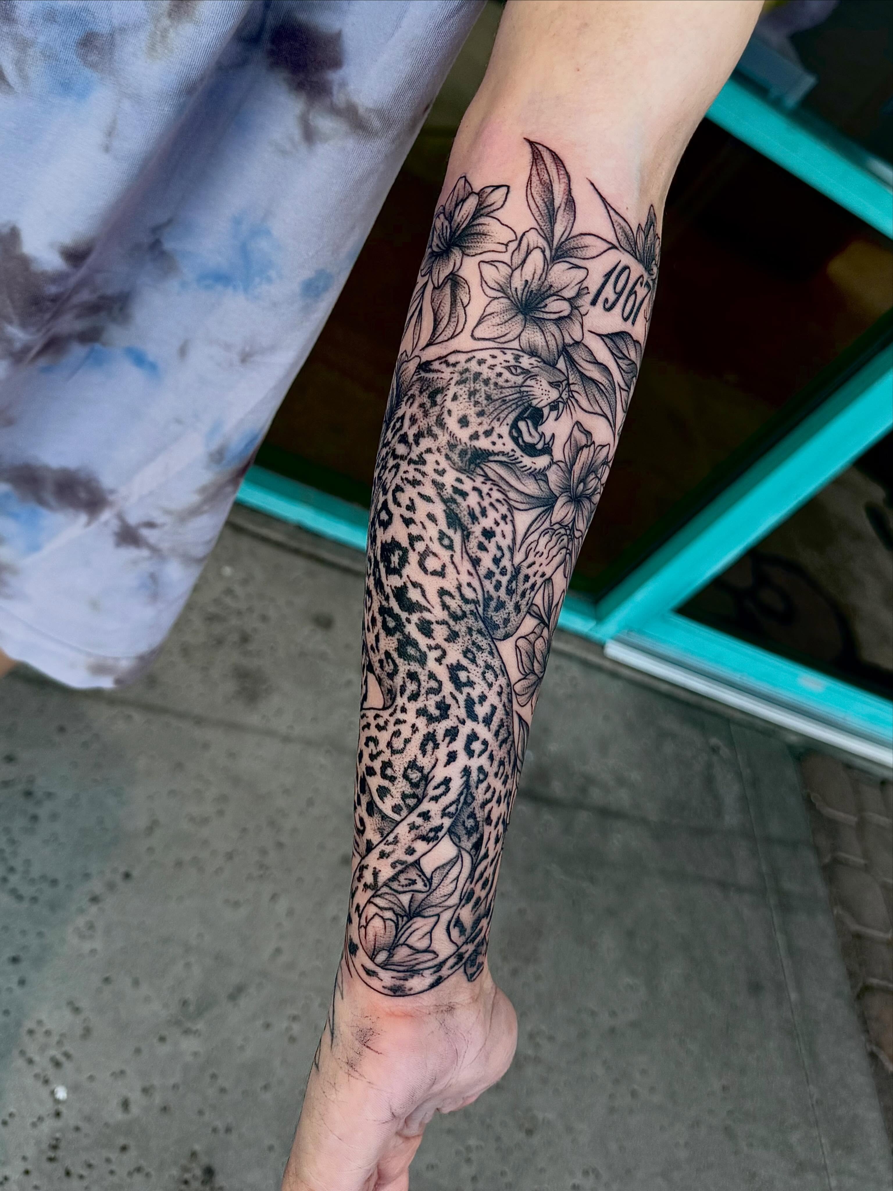 Leopard and flowers realism tattoo on the forearm by McKenna Hughes
