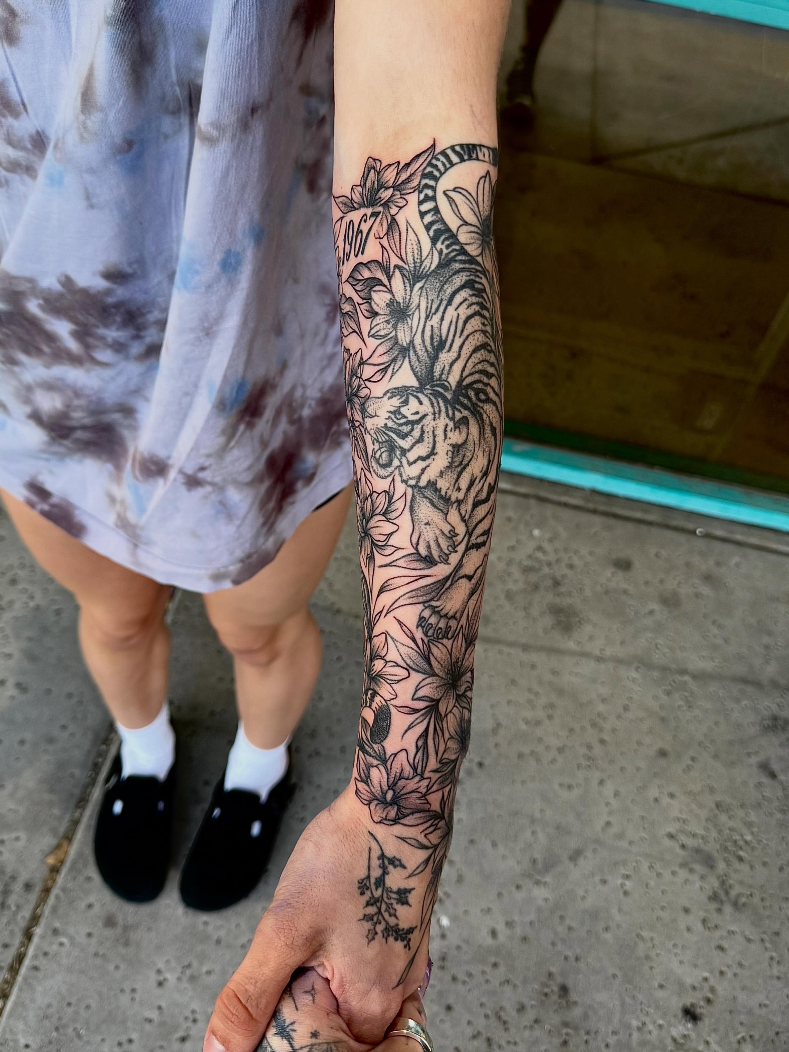 Tiger and floral black and grey tattoo on the forearm by McKenna Hughes