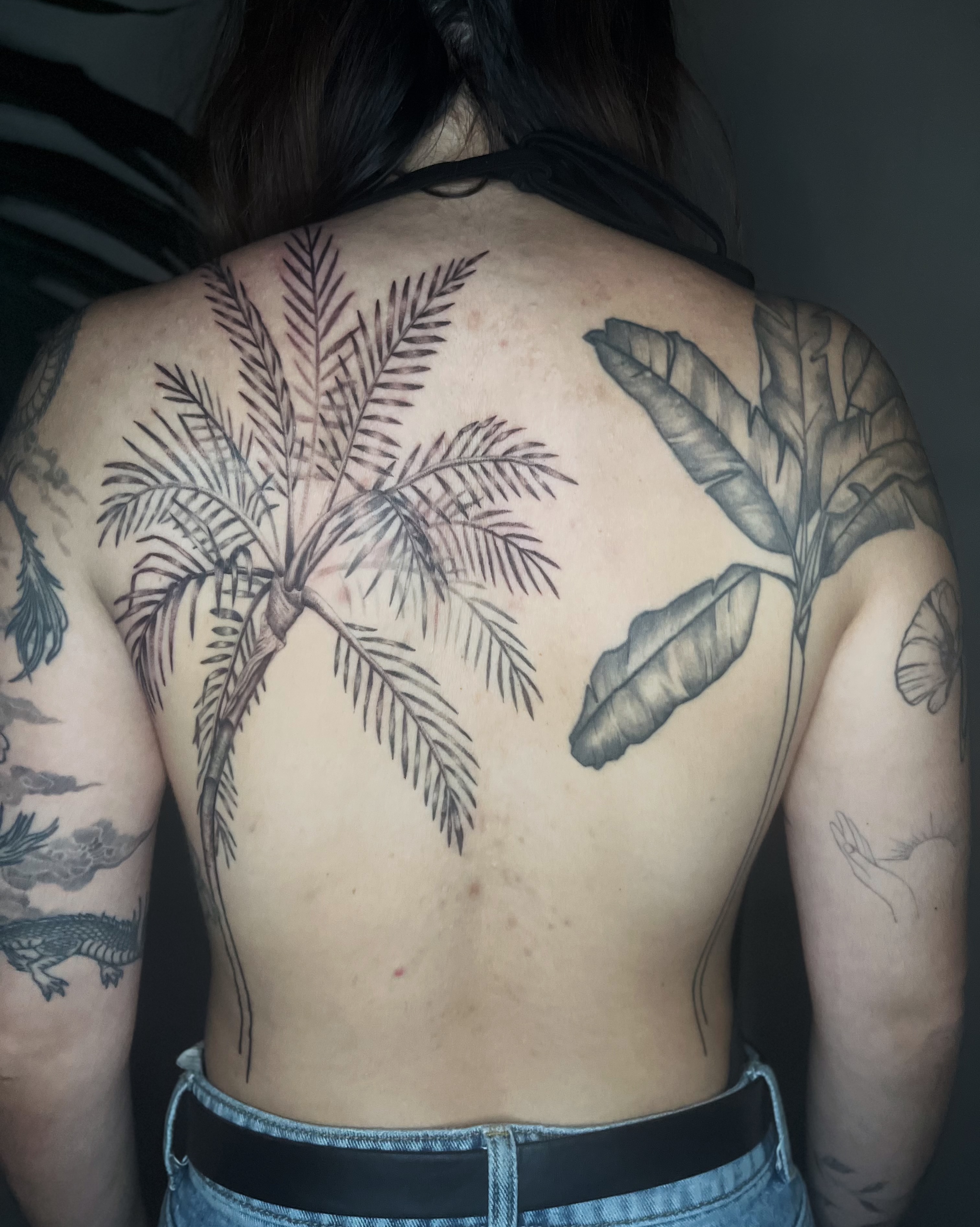 Palm tree and banana leaf black and grey tattoo on the back by Abigail, San Francisco, California