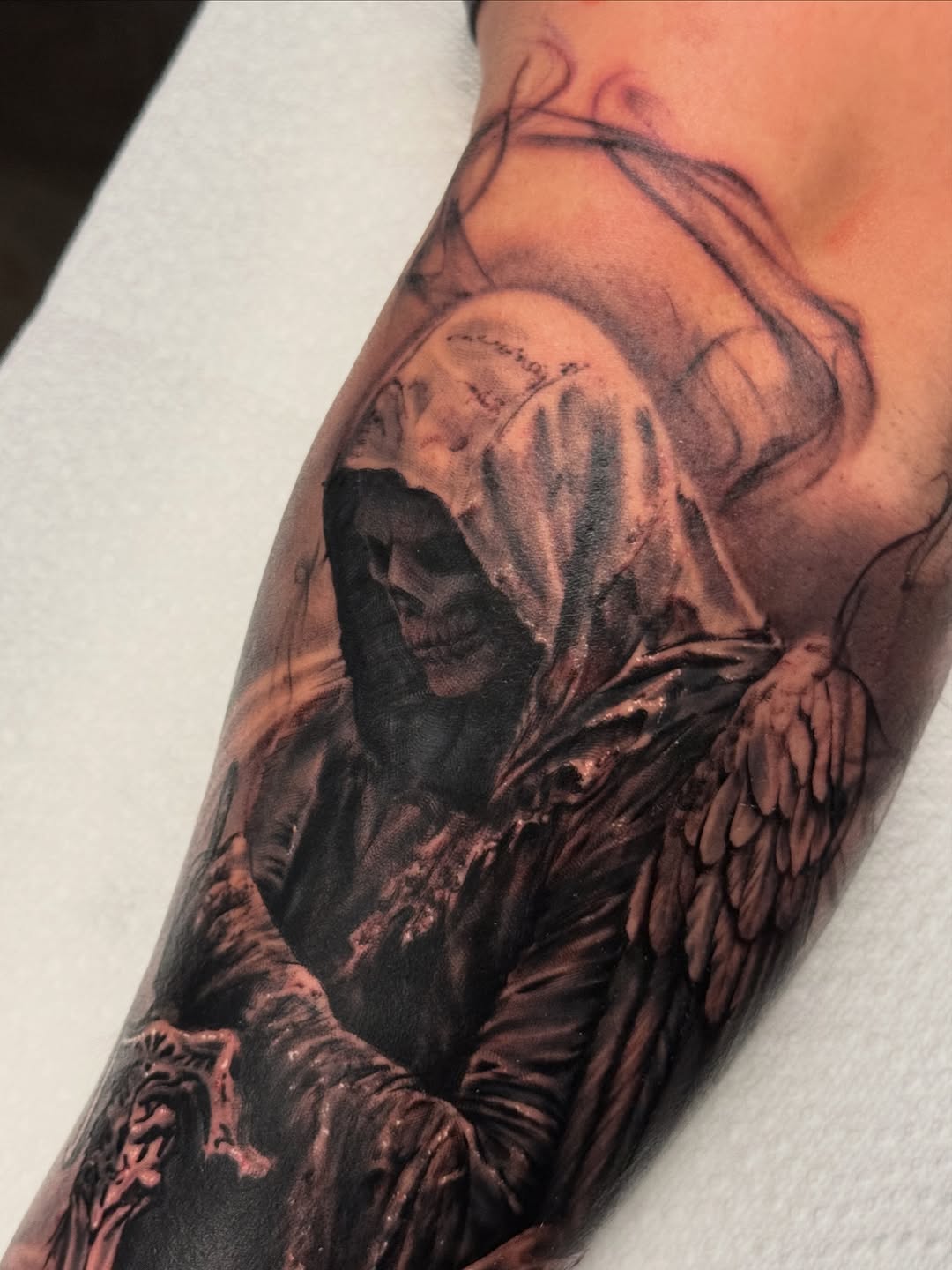 Grim reaper with wings realism tattoo on the forearm by Justin Hay