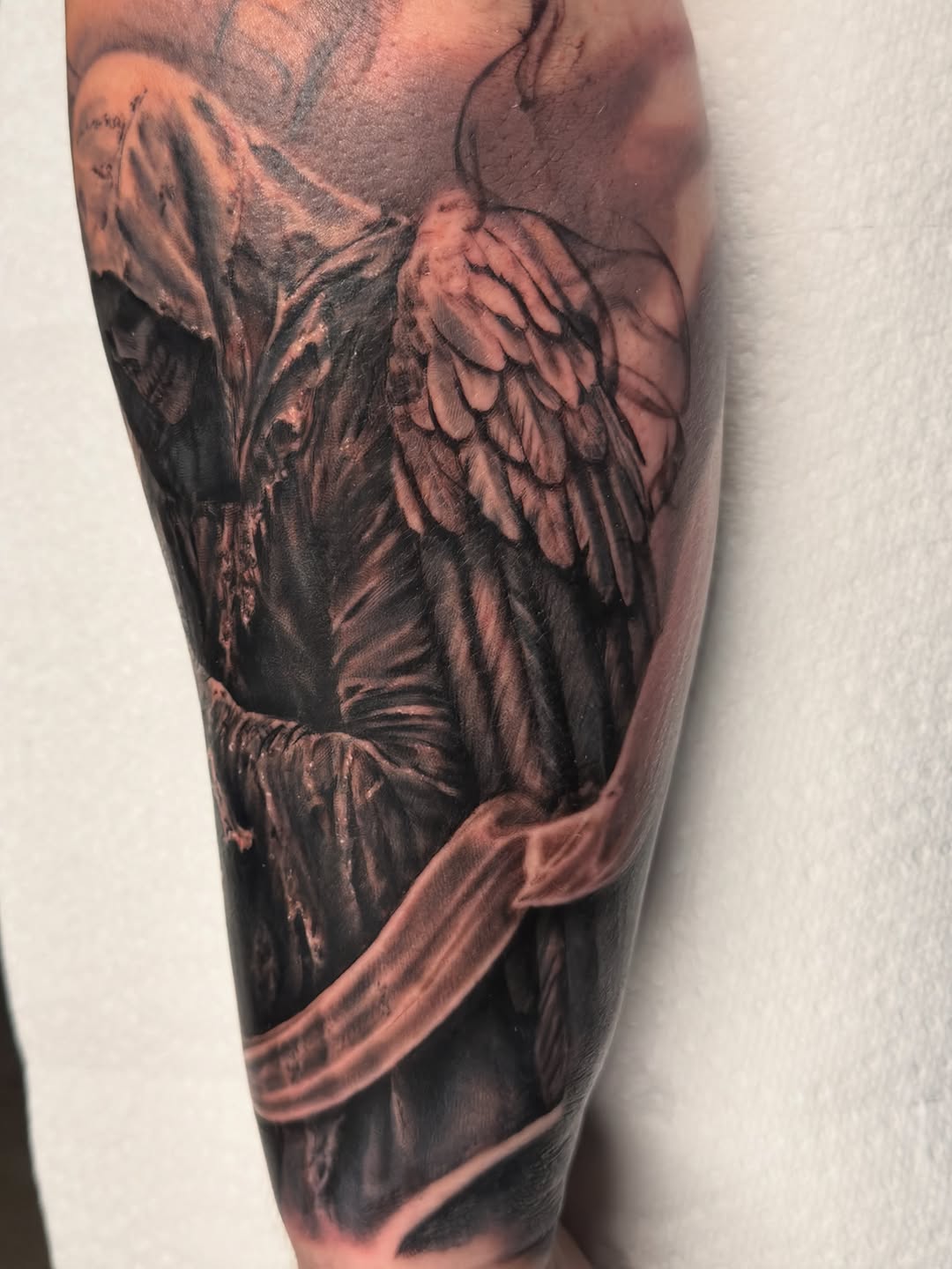 Grim reaper with wings realism tattoo on the forearm by Justin Hay