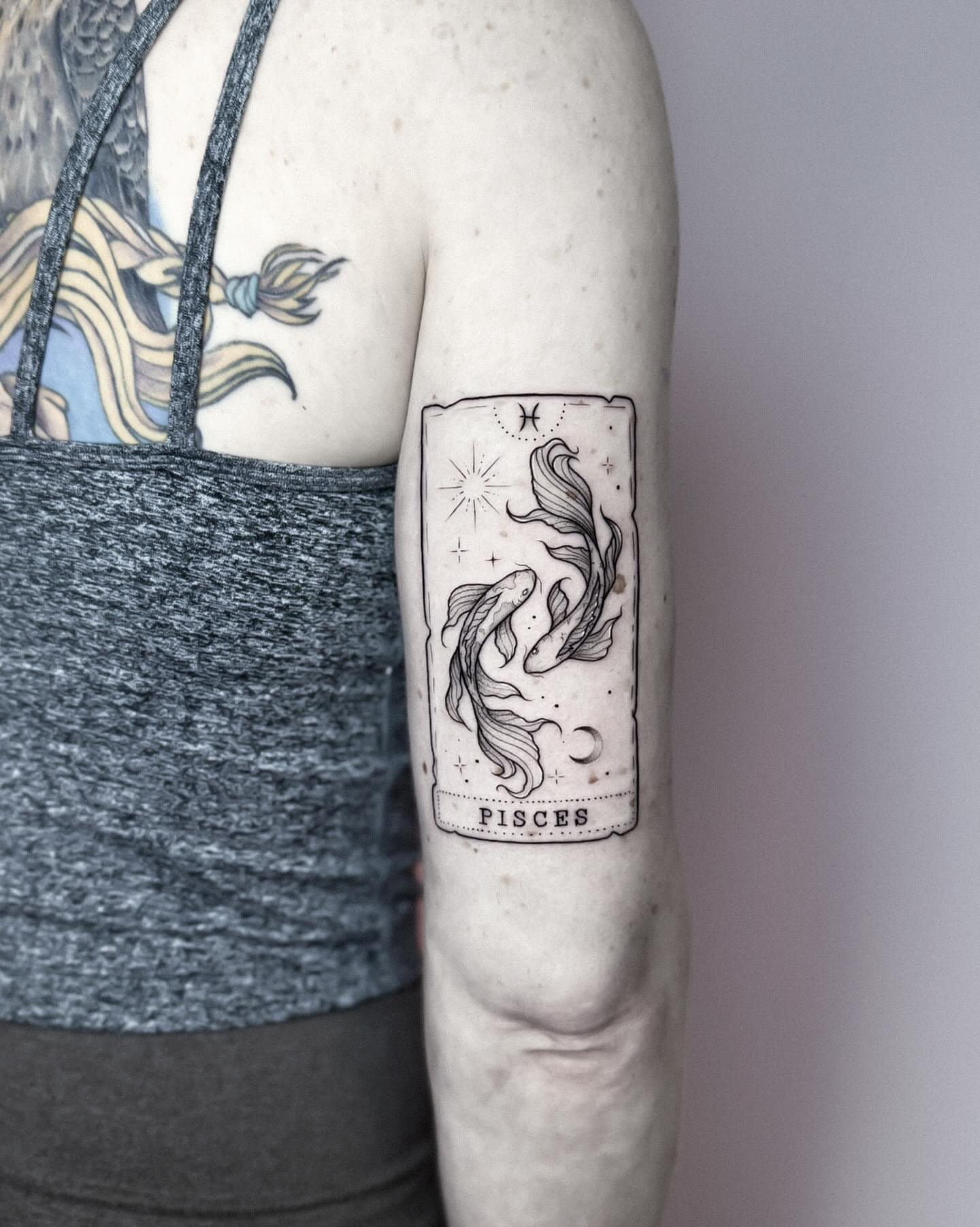 Pisces zodiac sign black and grey tattoo on the forearm by Whimsical Tattoos