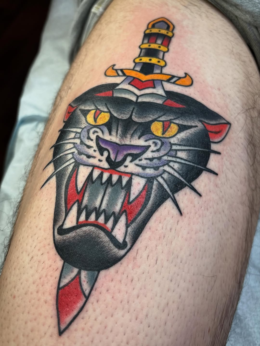 Panther head and dagger realism tattoo on the thigh by Tom Wenzell