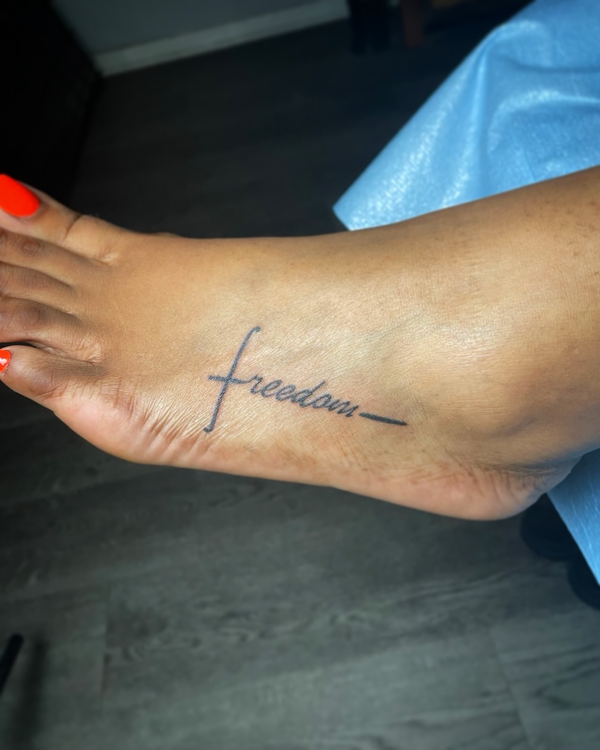 Freedom lettering script tattoo on the foot by The Reelist Ink