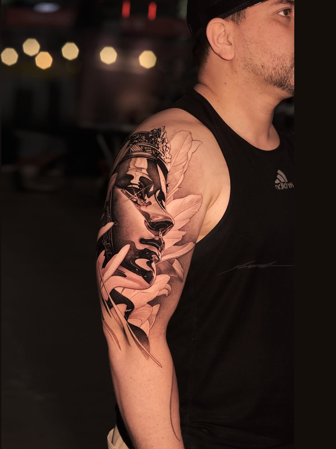 Woman's face with crown and flowers realism tattoo on the upper arm by Ke$la