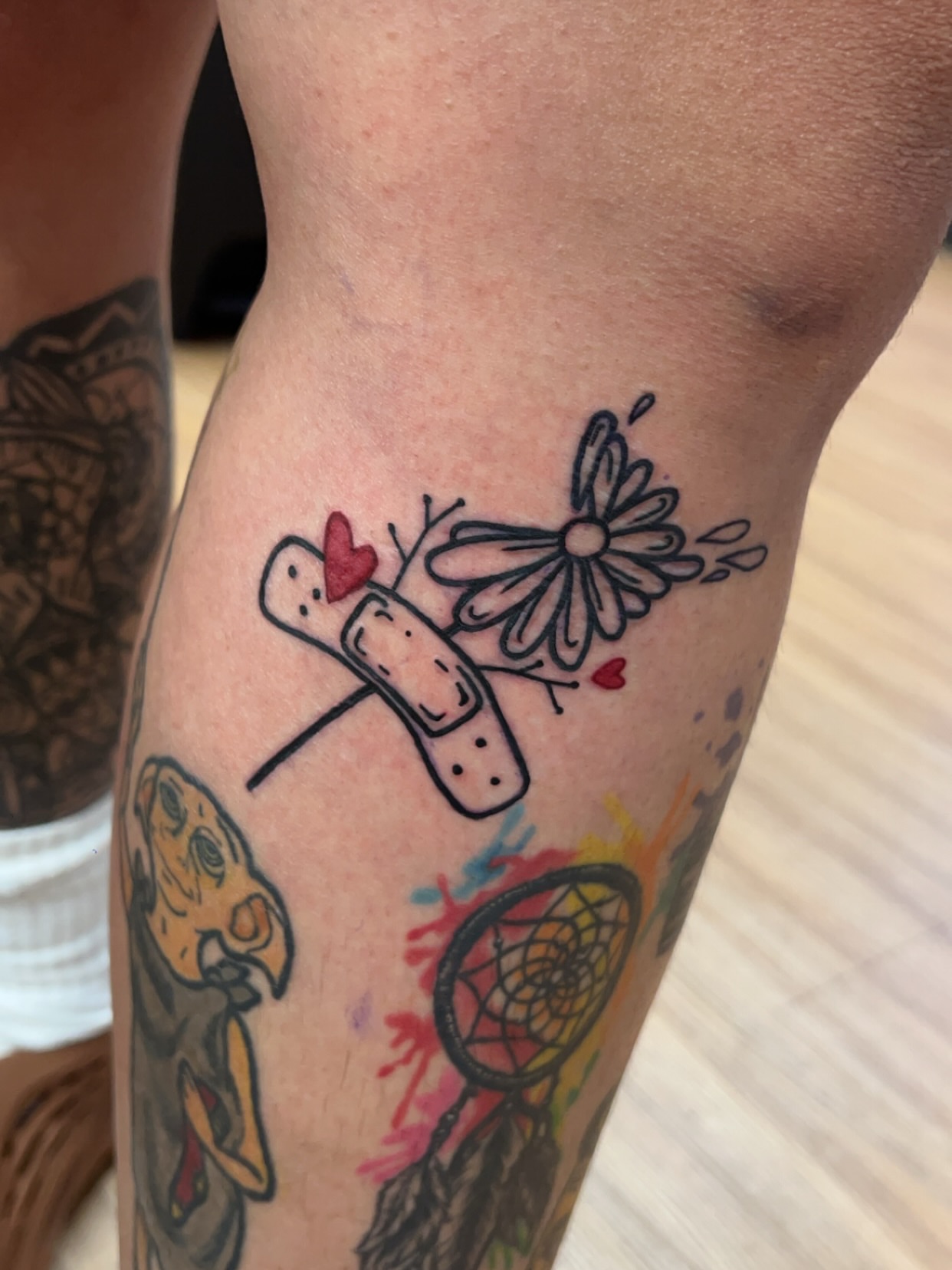 Band aid and flower American traditional tattoo on the forearm by Royal Martinez