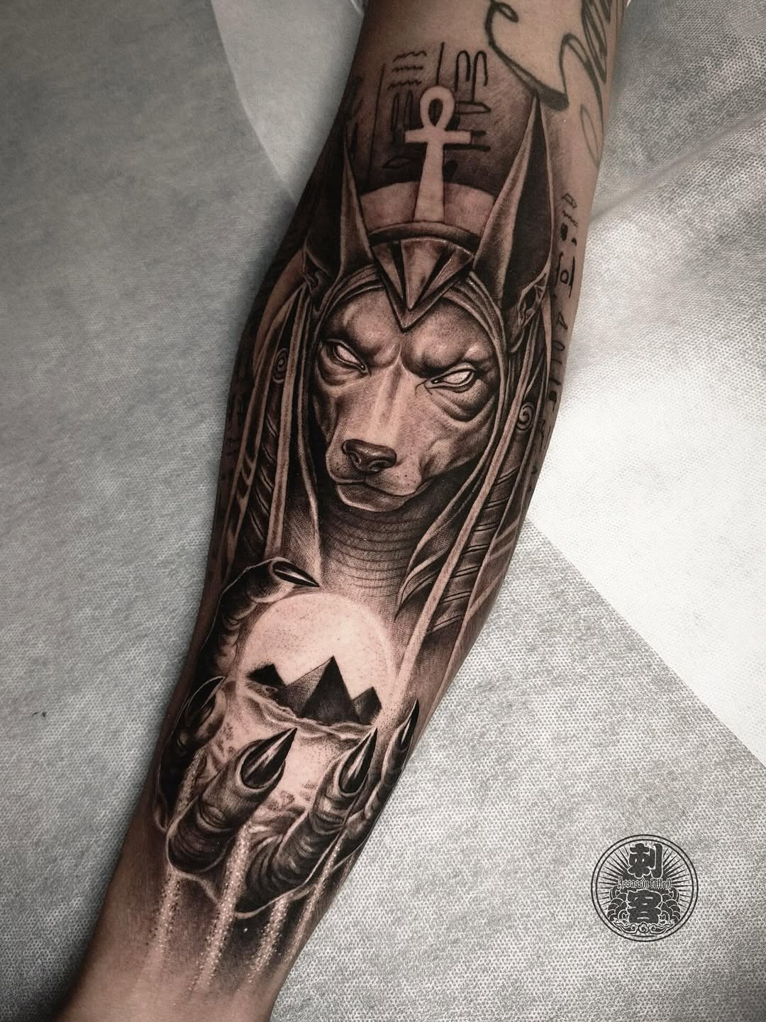 Anubis holding pyramids realism tattoo on the forearm by Duo