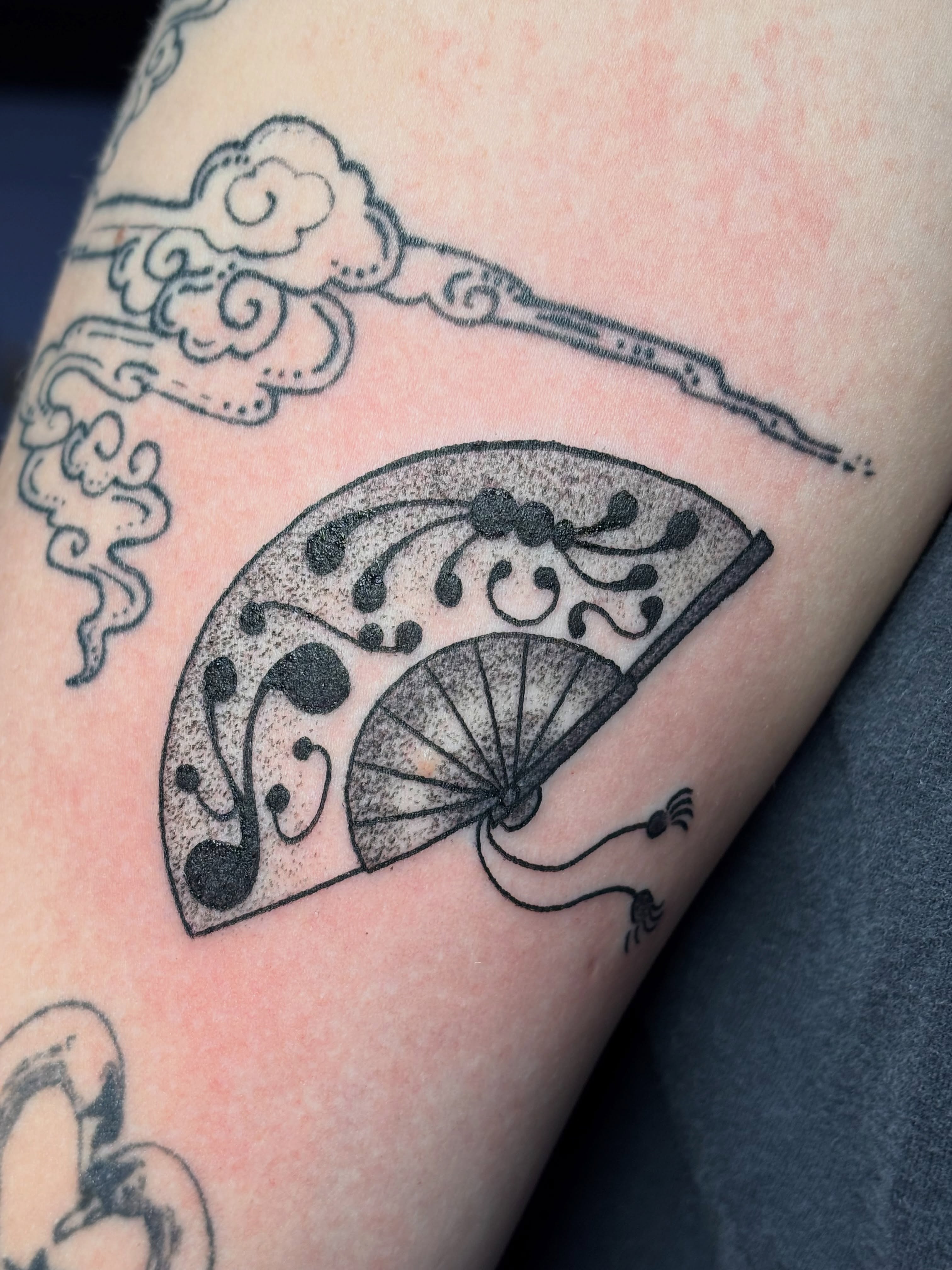 Fan and clouds black and grey tattoo on the forearm by Nina C., Eugene, Oregon