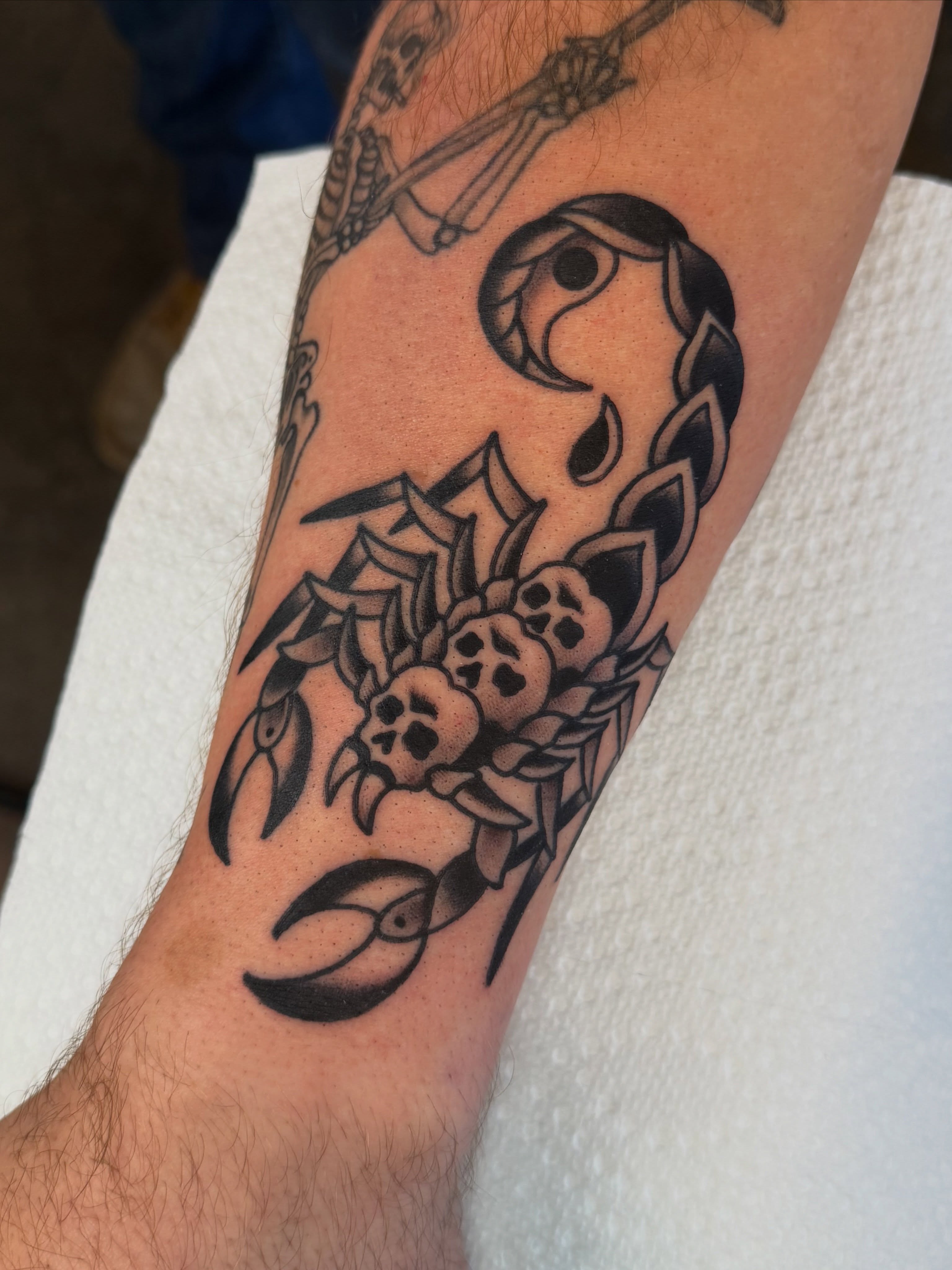 Scorpion and skulls American traditional tattoo on the forearm by Christopher Mikesell