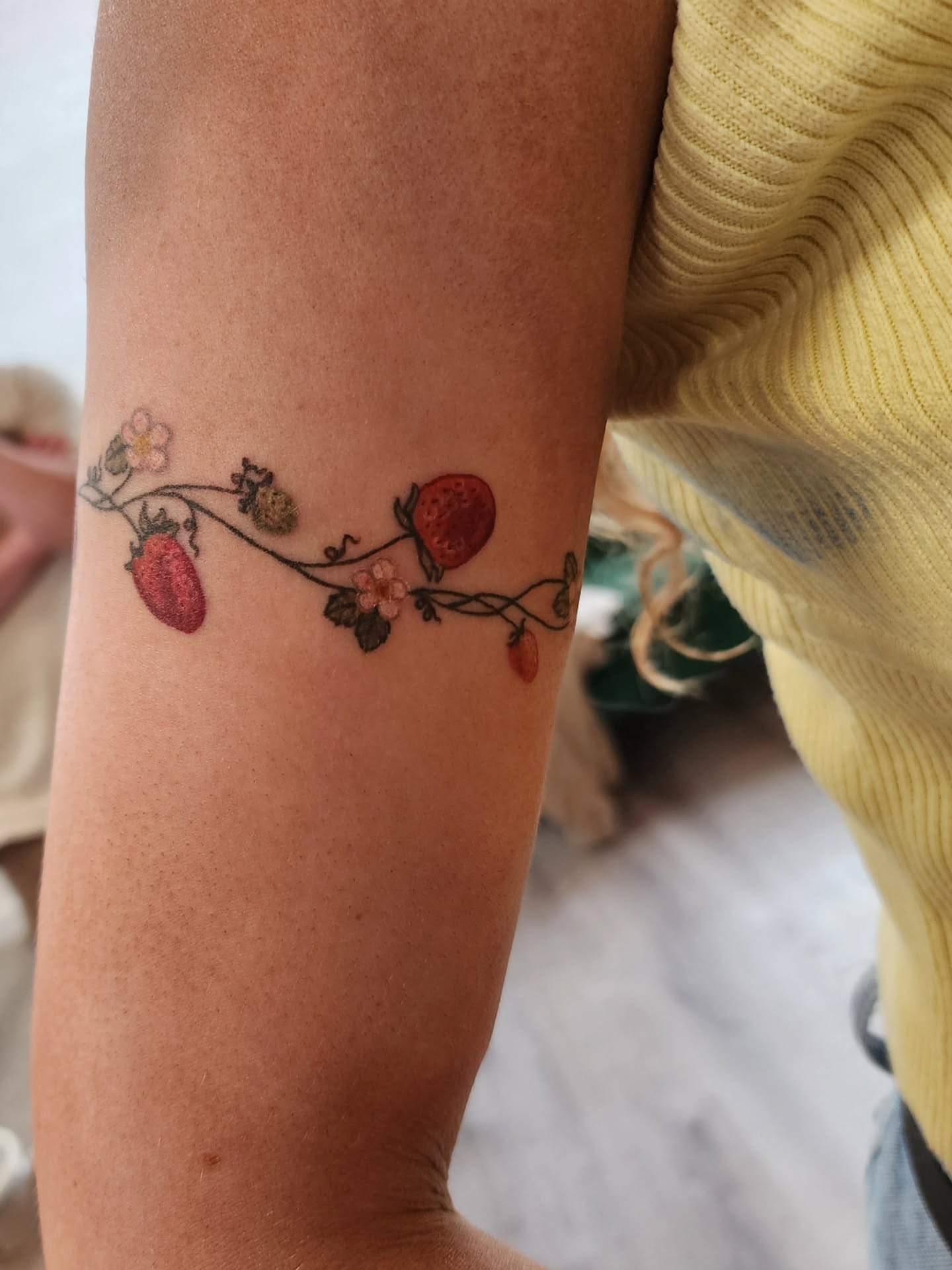 Strawberries and flowers watercolor tattoo on the forearm by mikayla