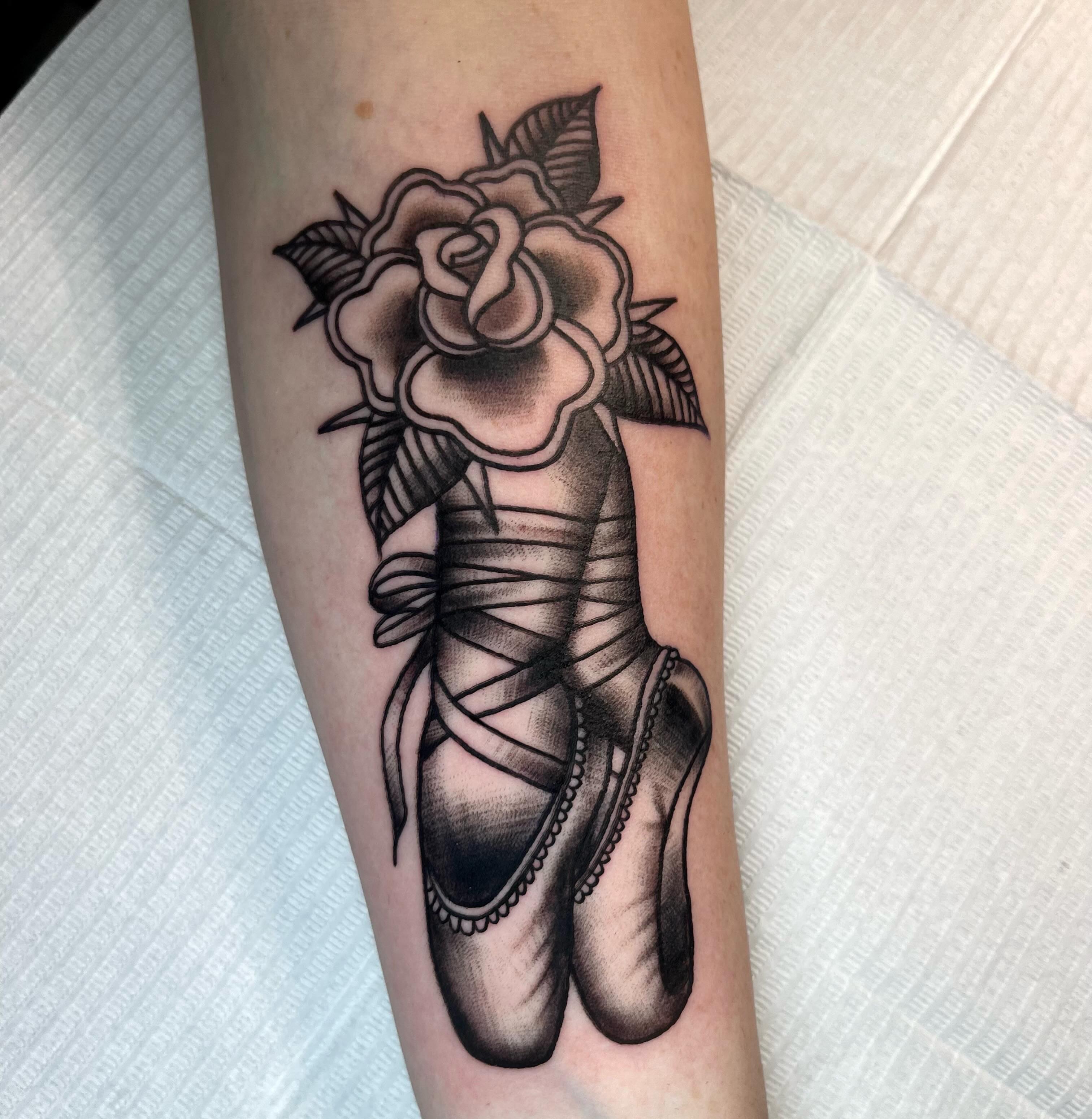 Ballerina shoes and rose realism tattoo on the forearm by Brooke Kresco