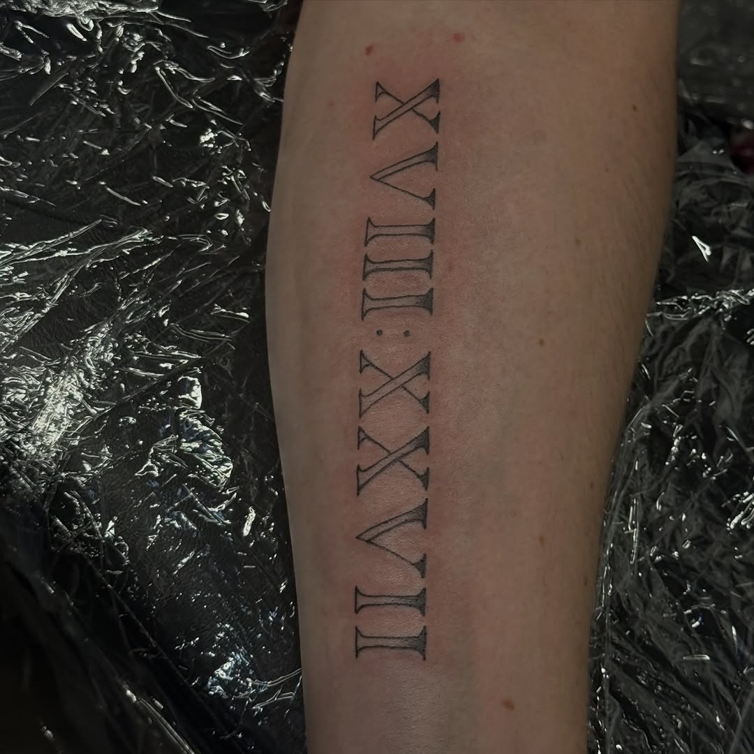 Roman numerals lettering tattoo on the forearm by licensed charlotte tattoo artist