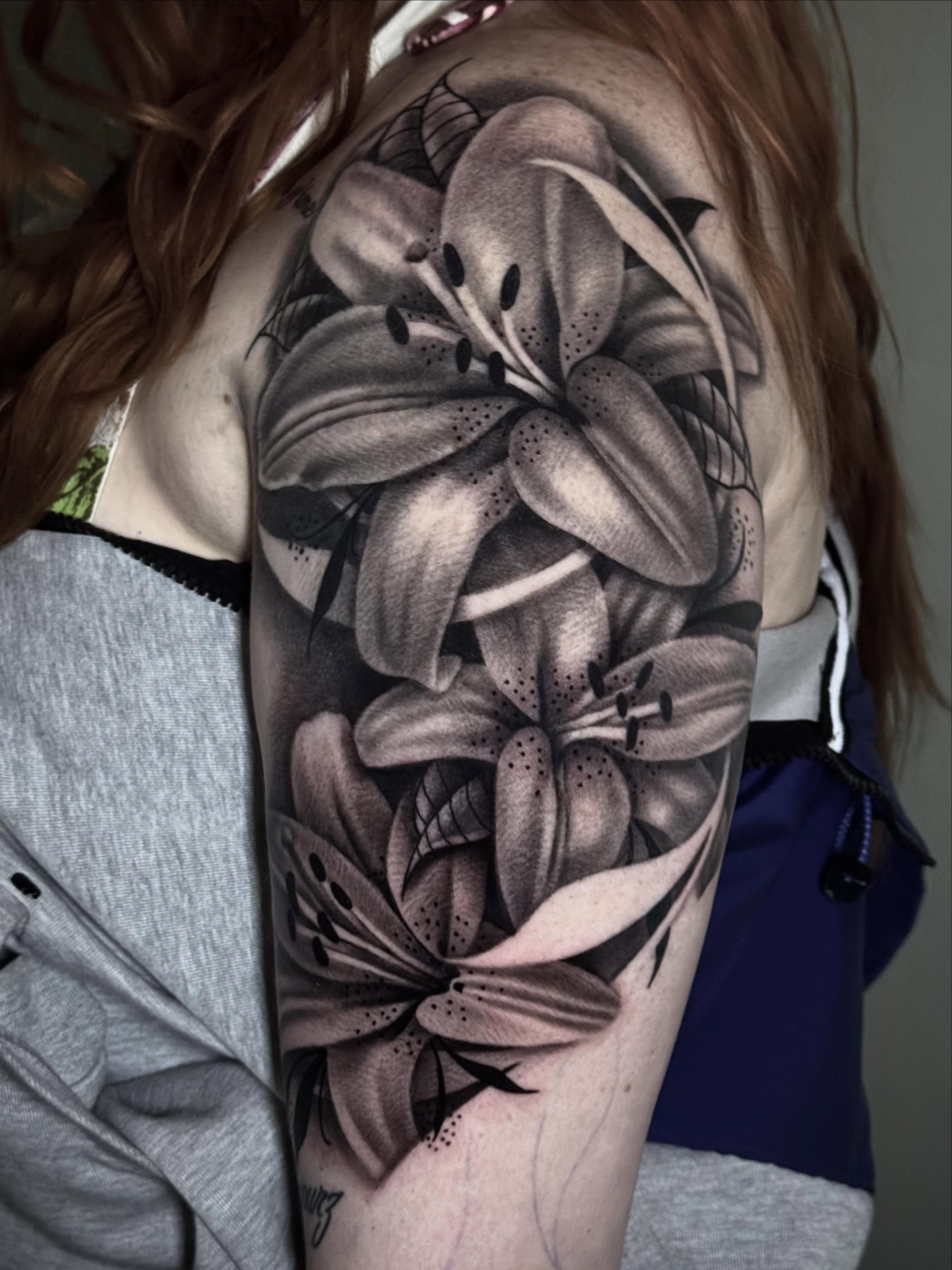 Lilies fine line tattoo on the upper arm by Tony Garcia