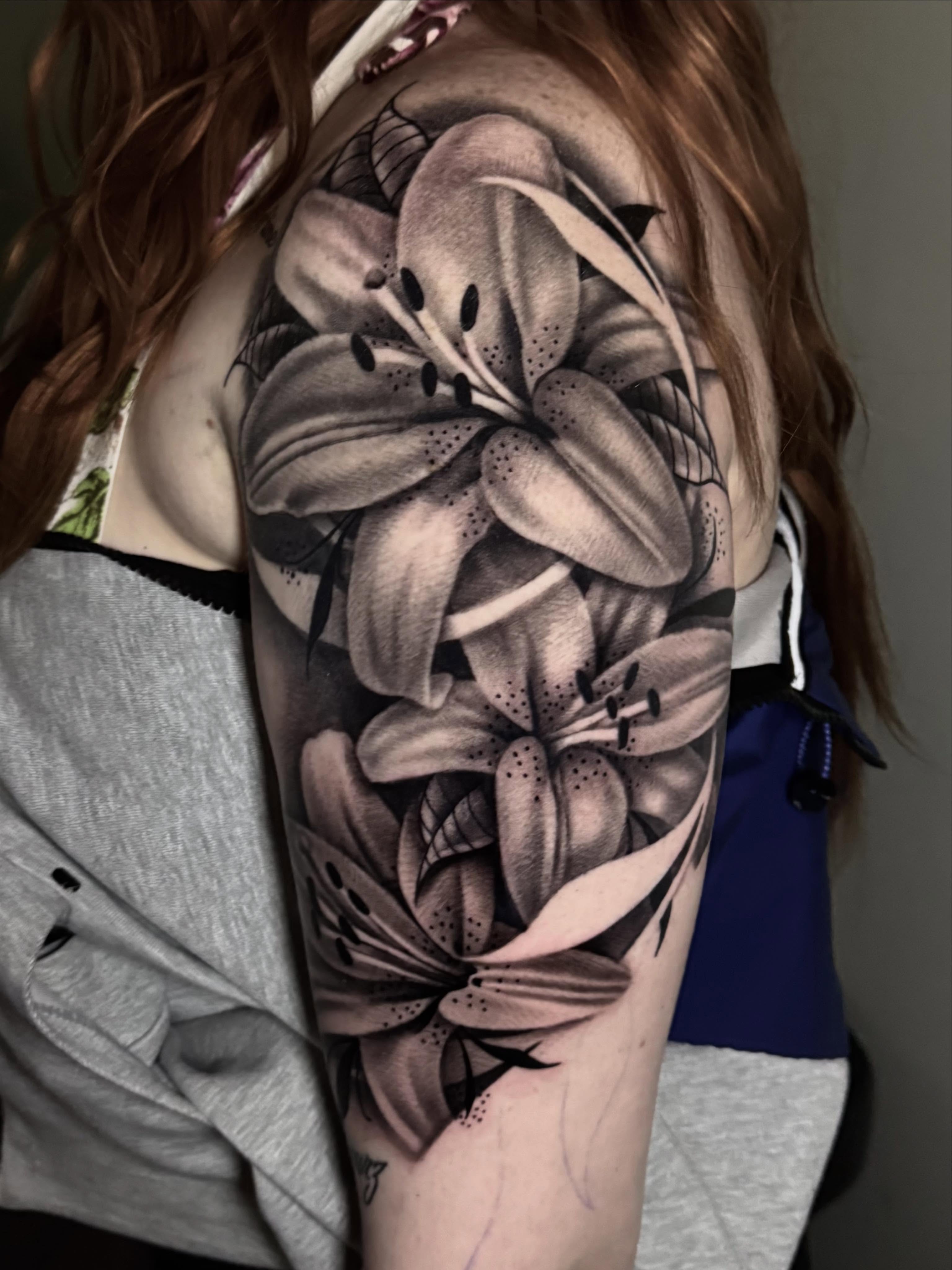 Lilies fine line tattoo on the shoulder by Tony Garcia