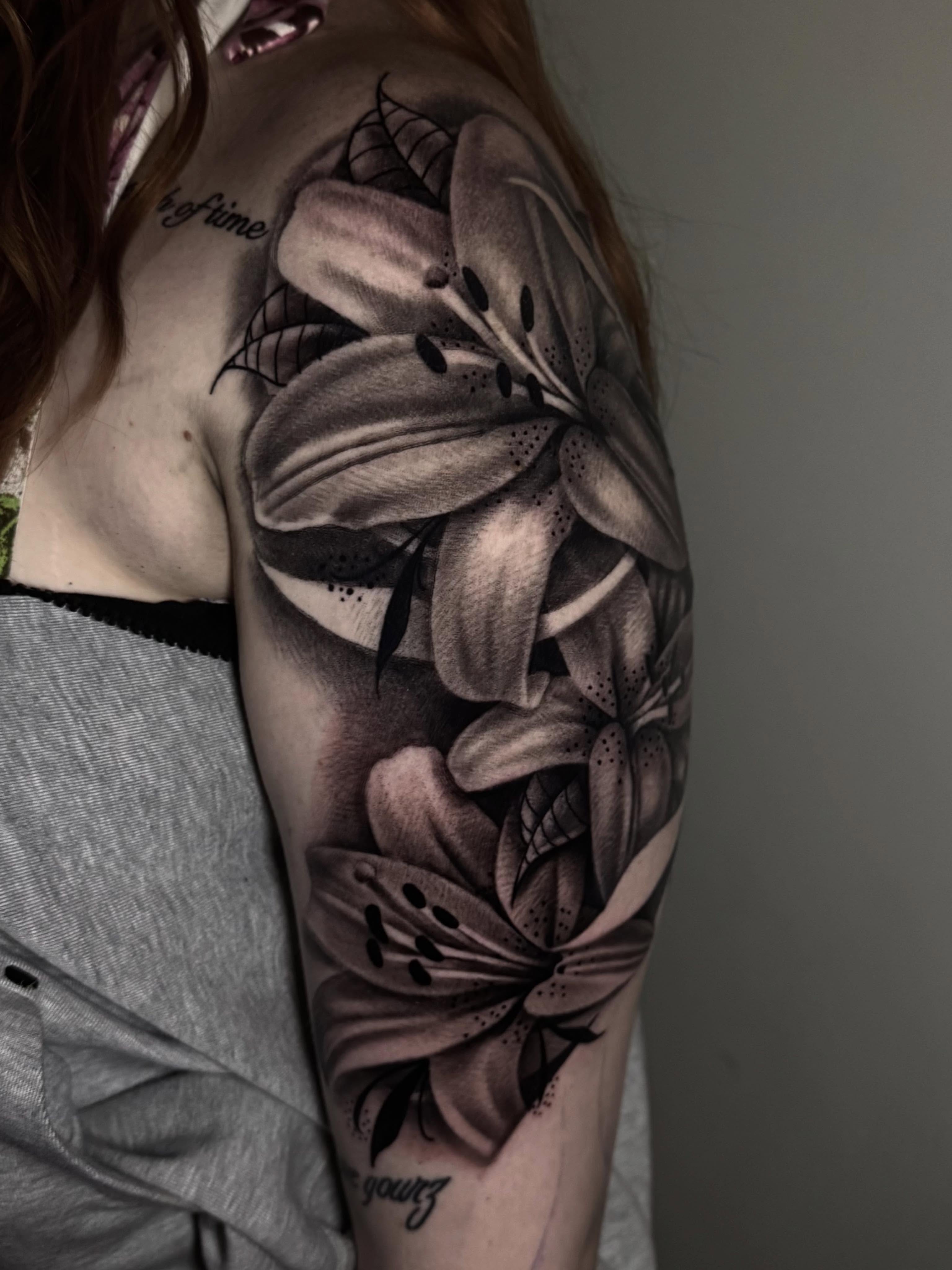 Lilies fine line tattoo on the upper arm by Tony Garcia