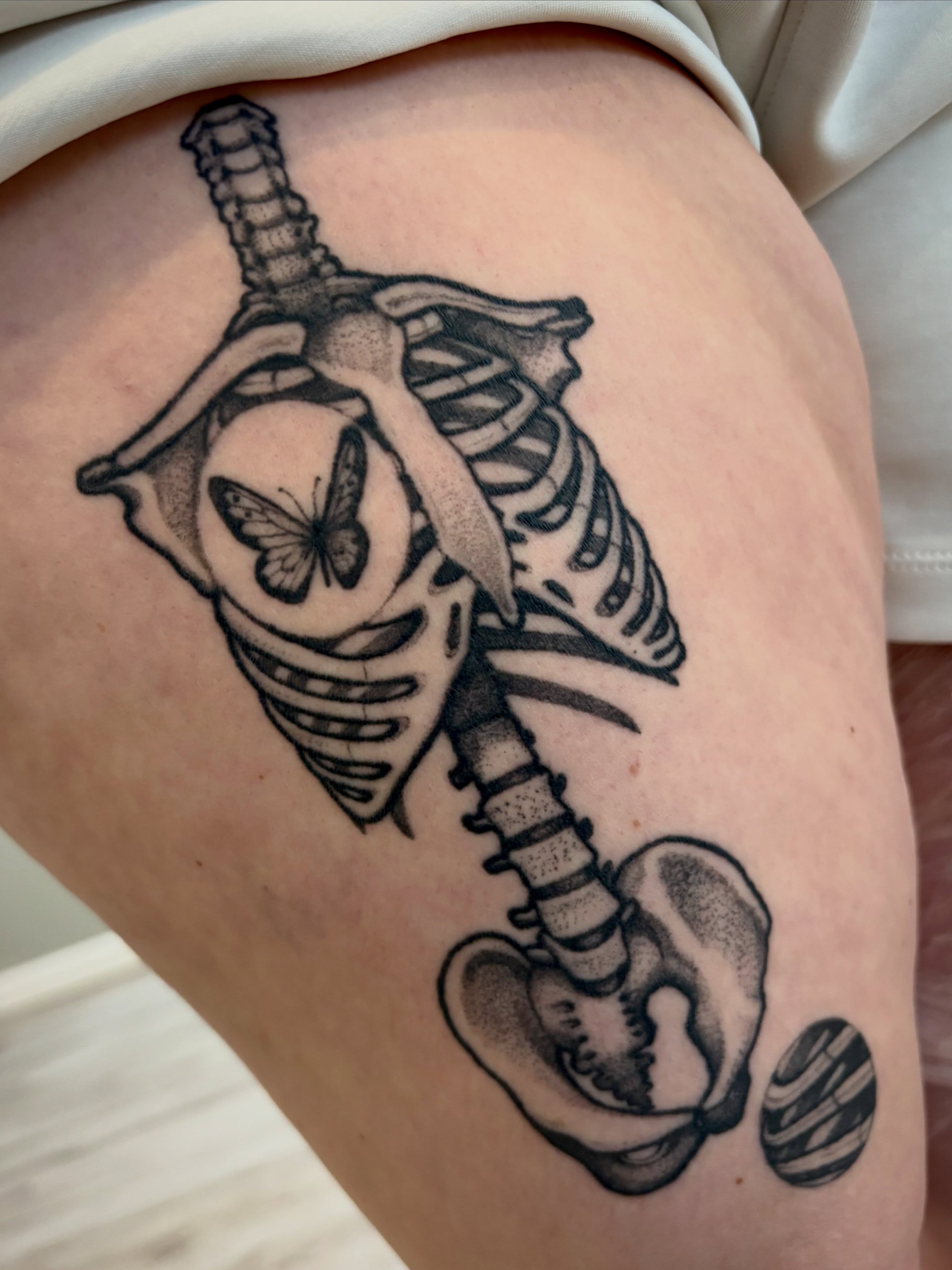 Skeleton with butterfly realism tattoo on the thigh by Tara, Exeter, Pennsylvania