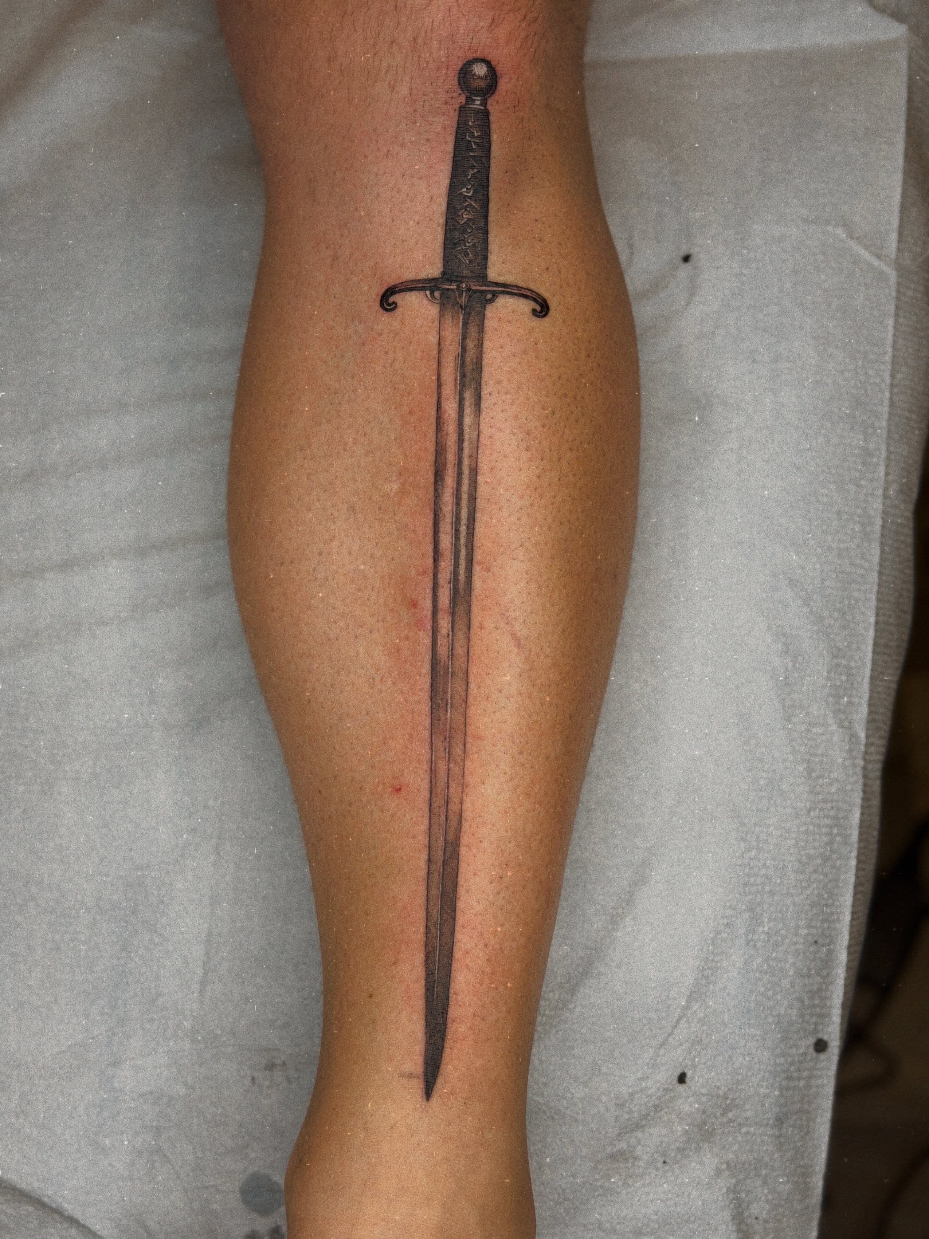Sword black and grey tattoo on the calf by Melissa Rose Moya