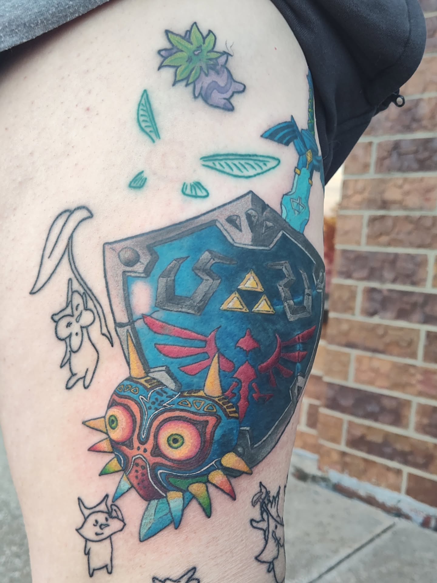 Majora's Mask and Hylian Shield new school tattoo on the thigh by Mercury