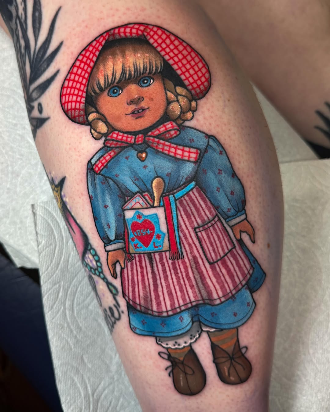 Rag doll realism tattoo on the thigh by Monica Amneus