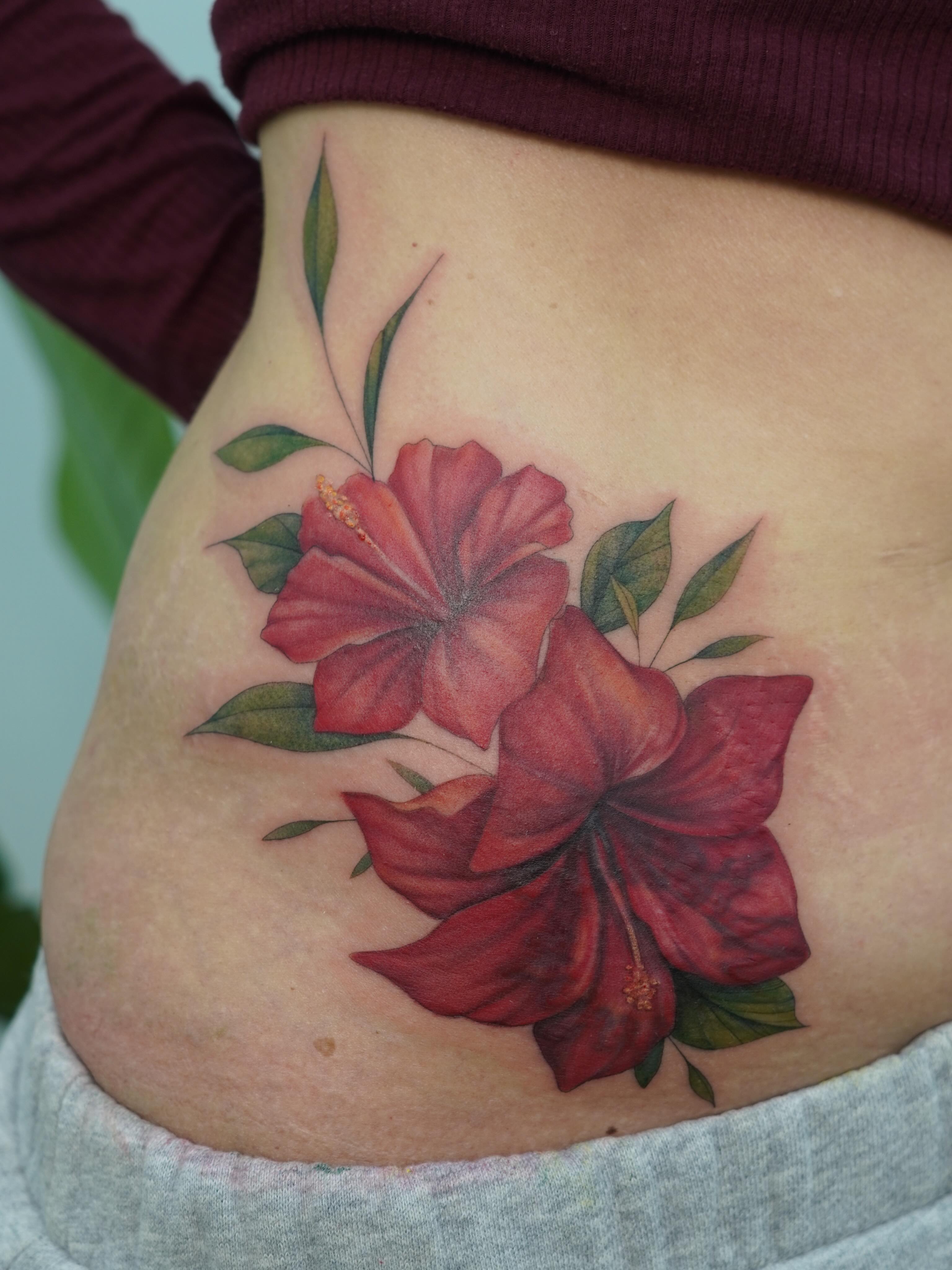 Red hibiscus flowers realism tattoo on the ribs by Danae Andino