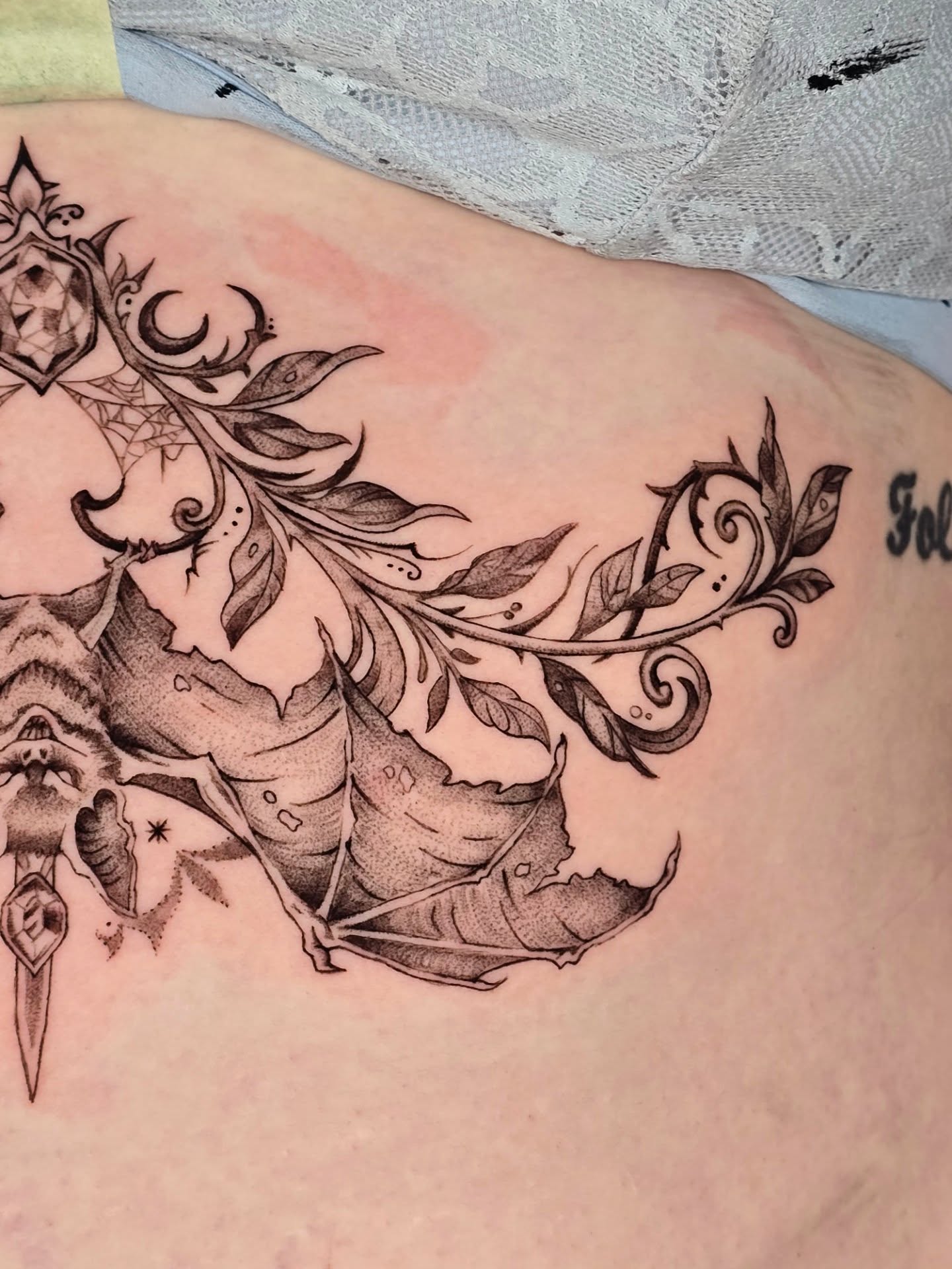 Feather and leaves black and grey tattoo on the thigh by Scribbles (Teala René), Charlotte, North Carolina