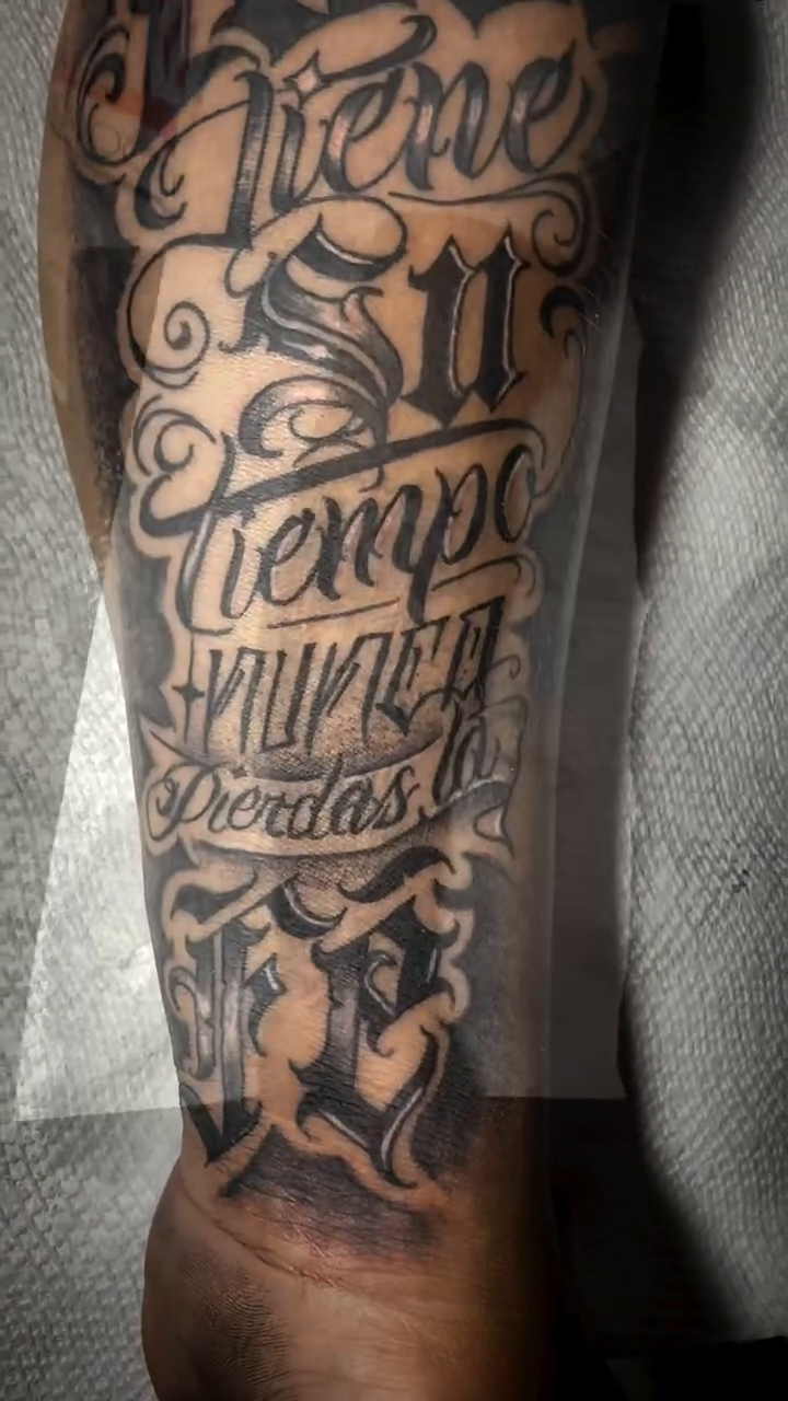 Script tattoo with ornamental elements Chicano tattoo on the forearm by Jonny Vicious