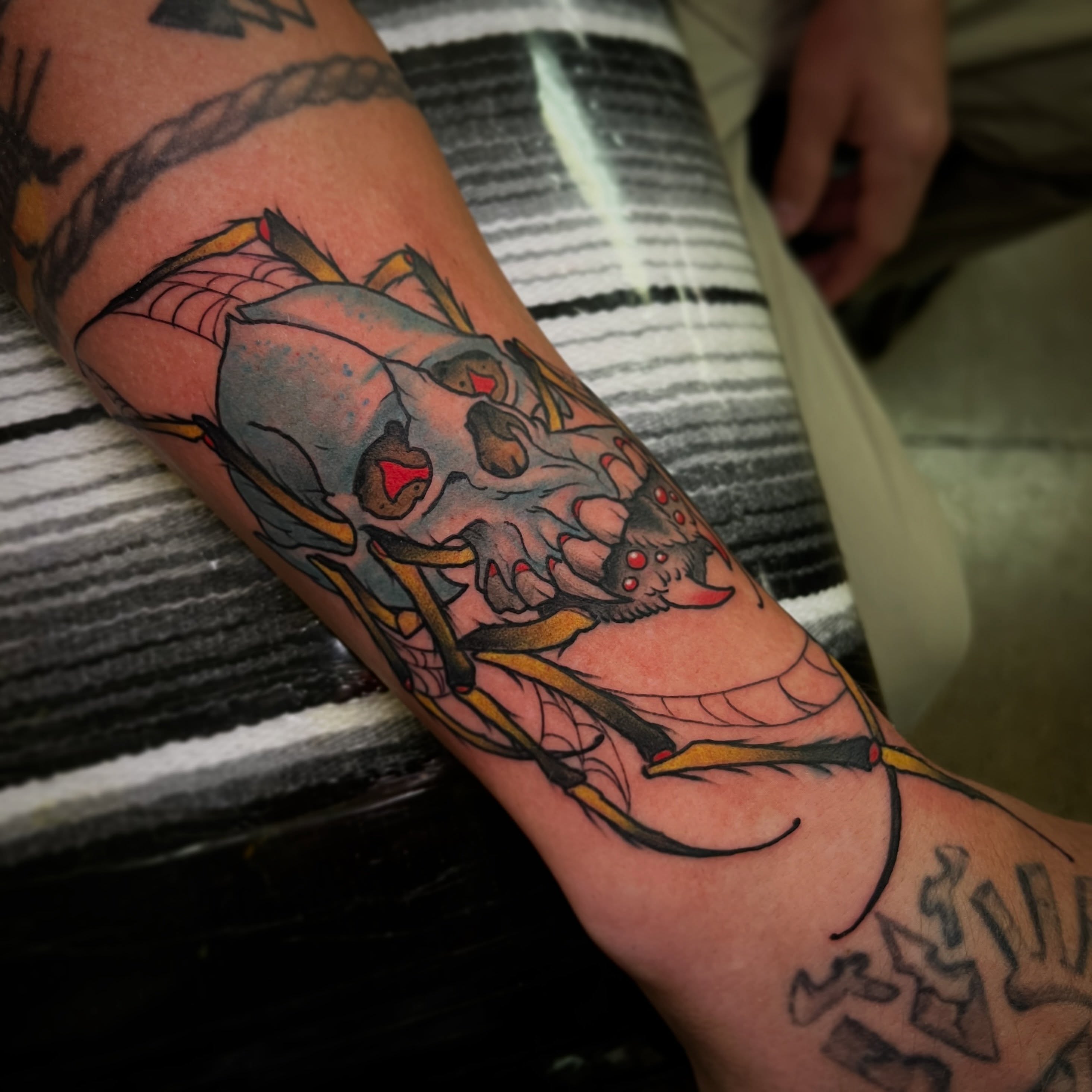Skull and bow American traditional tattoo on the forearm by Evan Perrine