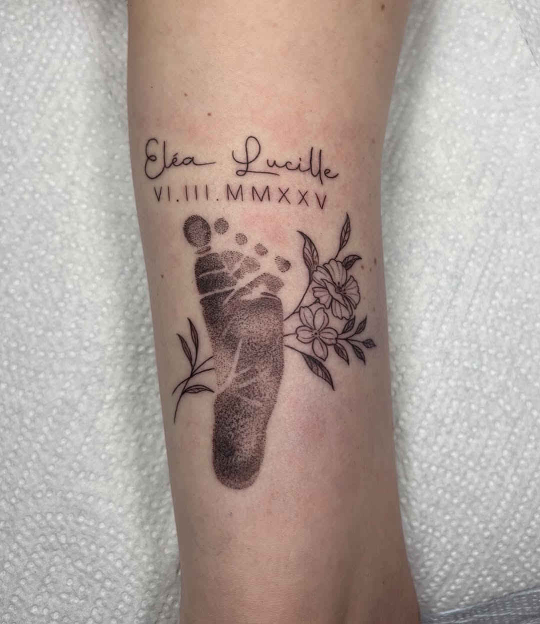 Baby footprint with name and date realism tattoo on the forearm by Fineline tattoos by Kinsey