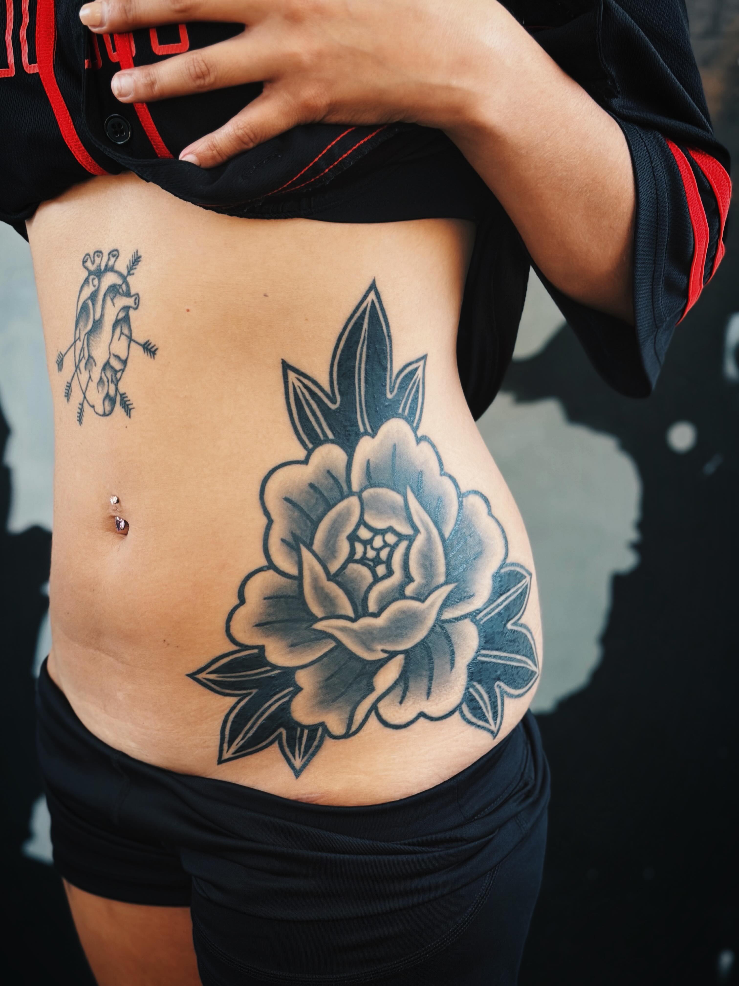 Flower black and grey tattoo on the torso by @amandahowtattoo
